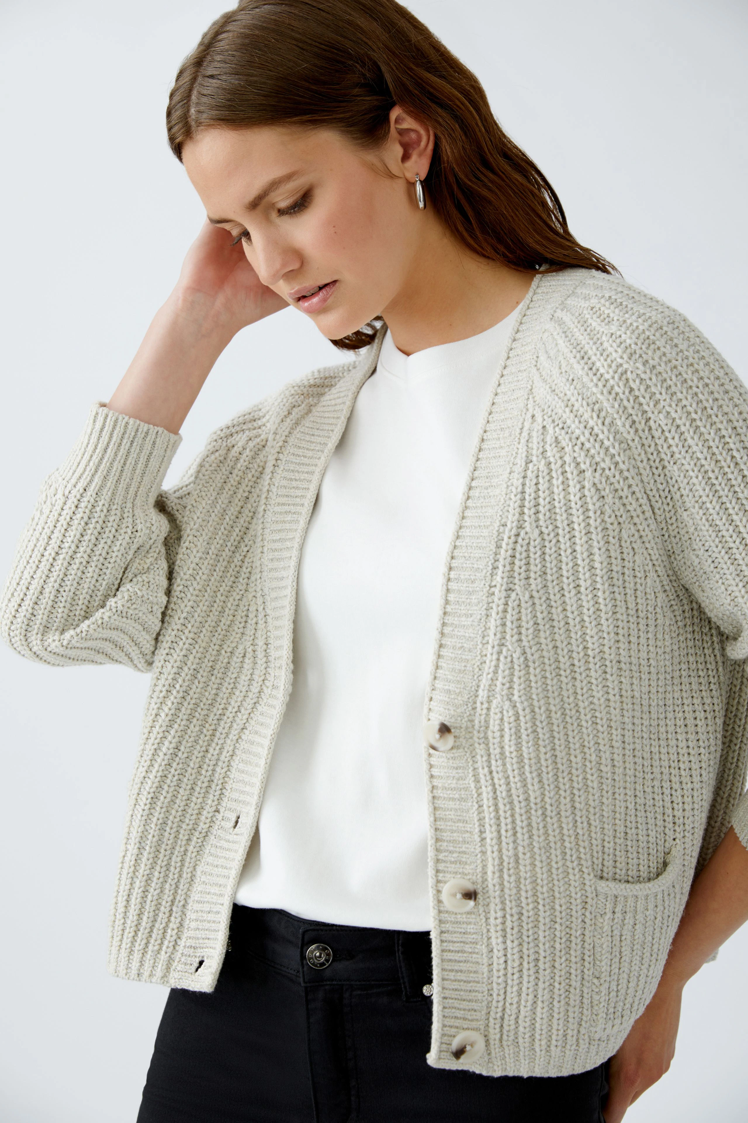 Casual women's cardigan: A woman in a light gray knitted cardigan with buttons and pockets.