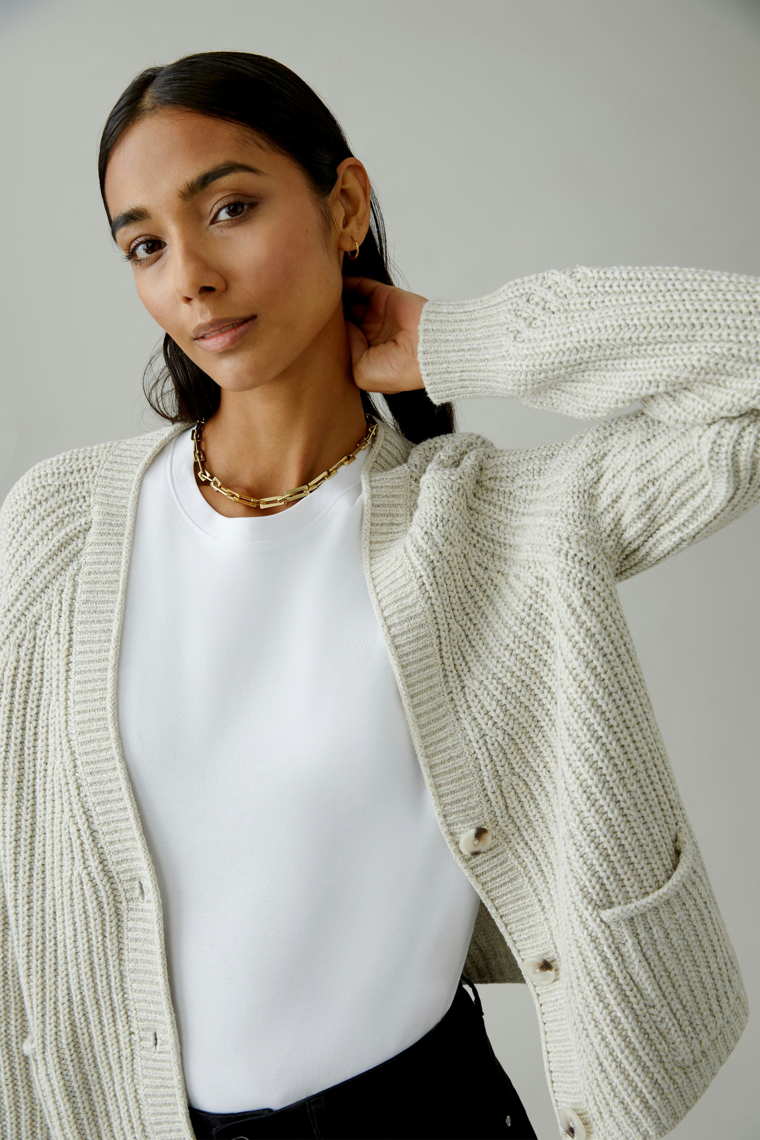 Bequeme Damen-Strickjacke: Frau in heller Strickjacke mit Taschen und lässigem T-Shirt.