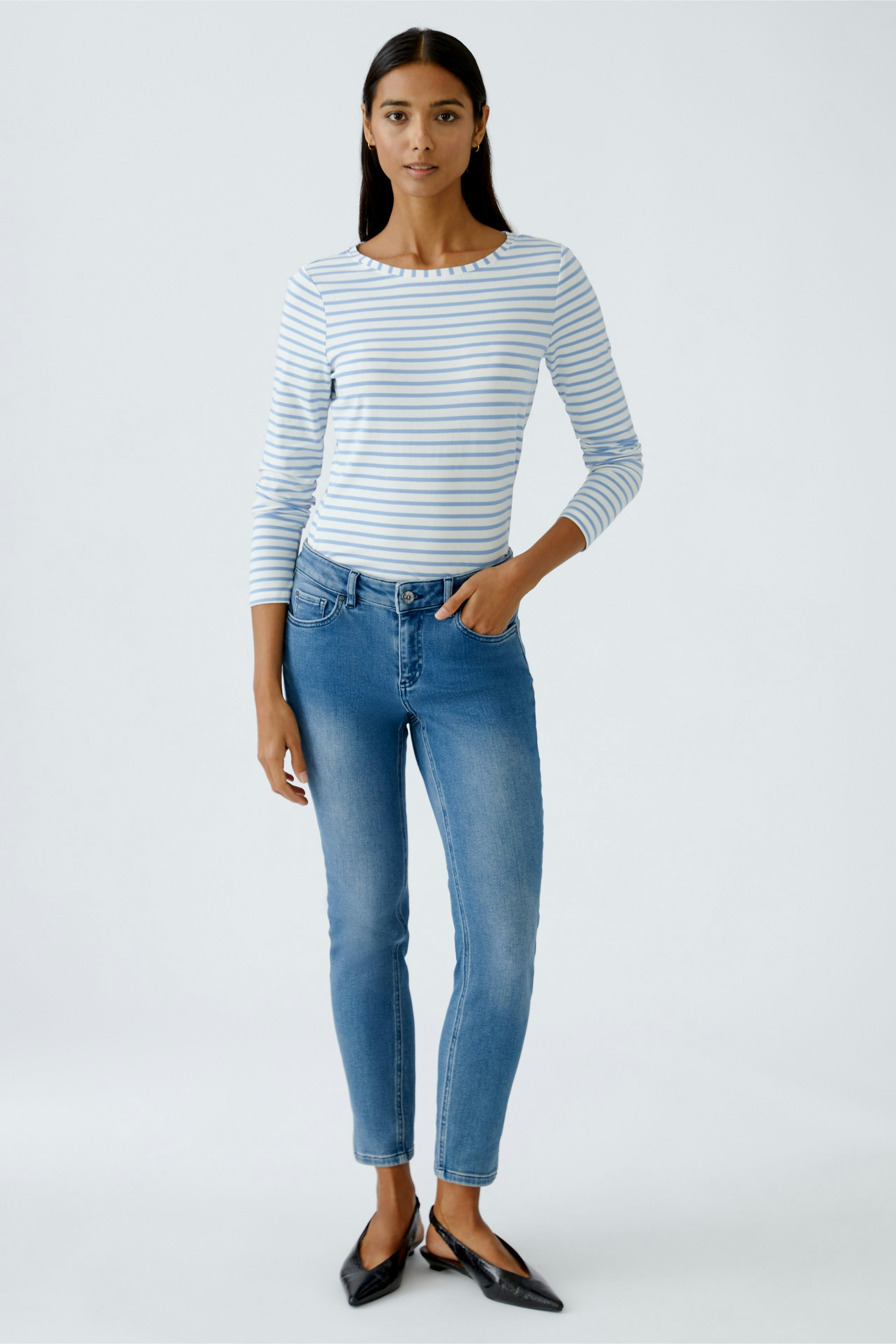 Casual long-sleeve shirt: Woman in a striped top paired with jeans, showcasing a relaxed style.