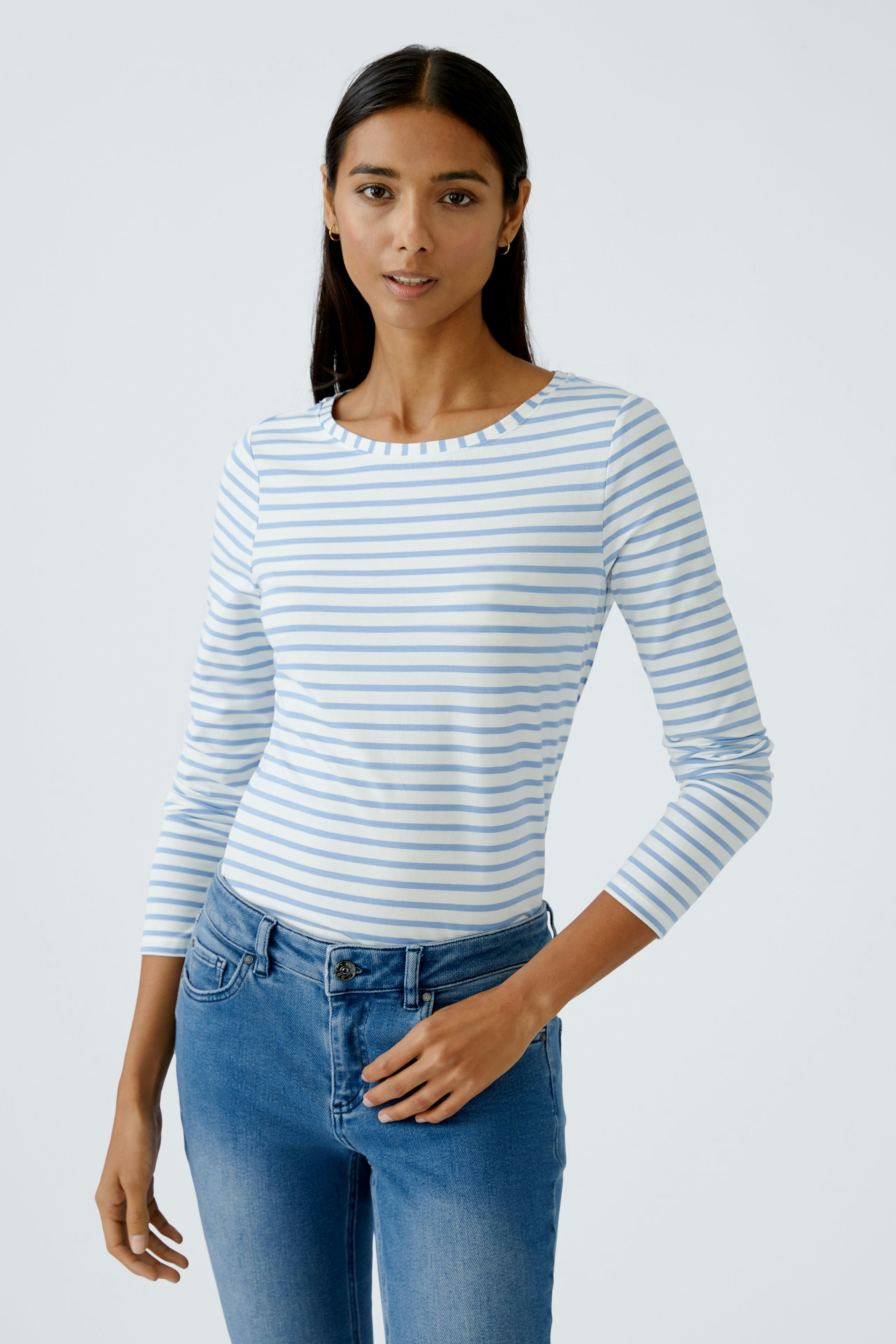 Casual long-sleeve shirt: Woman in a striped top paired with jeans, showcasing a relaxed style.