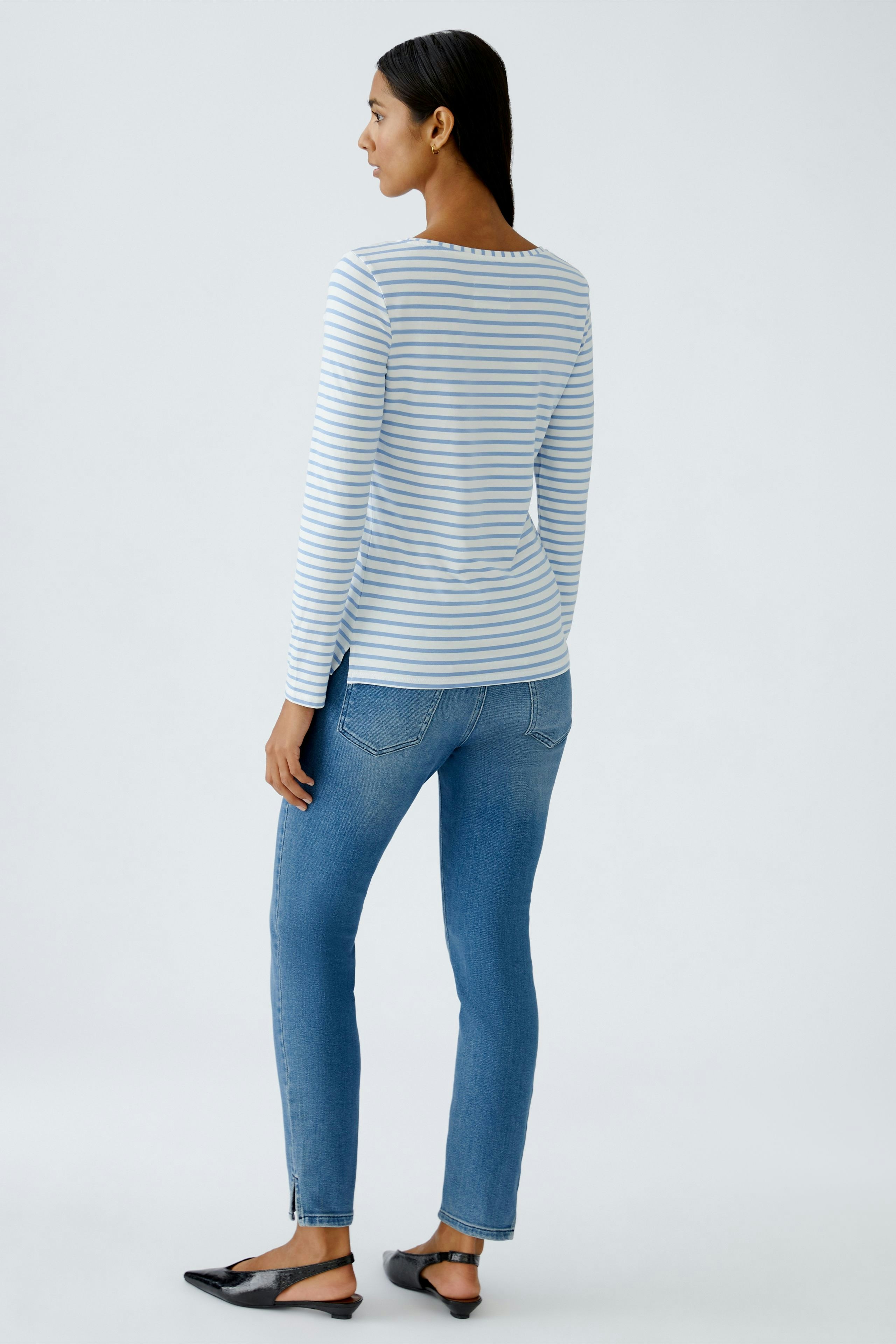 Casual long-sleeve shirt: Woman in a striped top paired with blue jeans, showcasing a relaxed style.