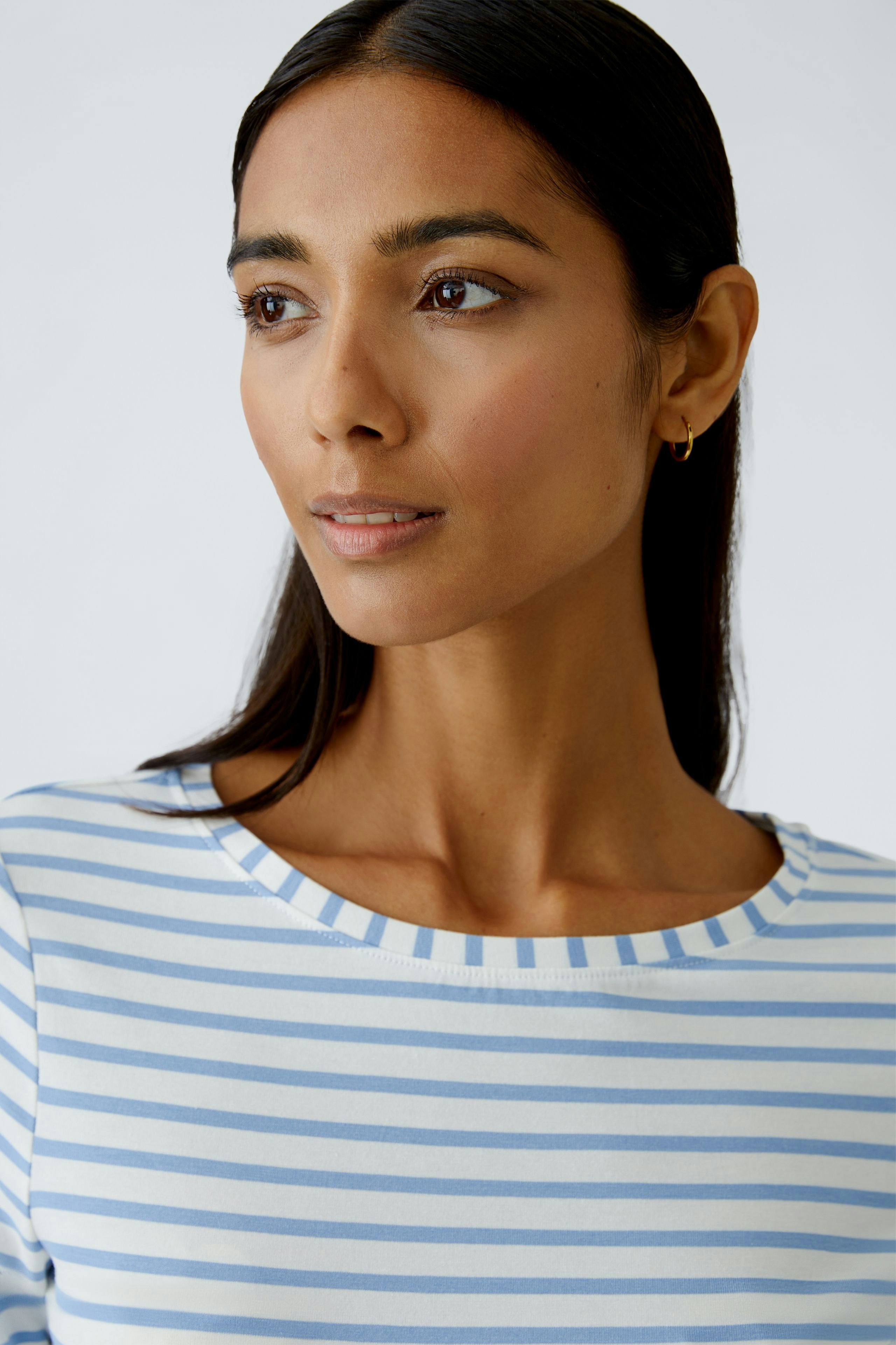 Casual long-sleeve shirt: Woman in a striped shirt with a round neckline, showcasing a relaxed style.