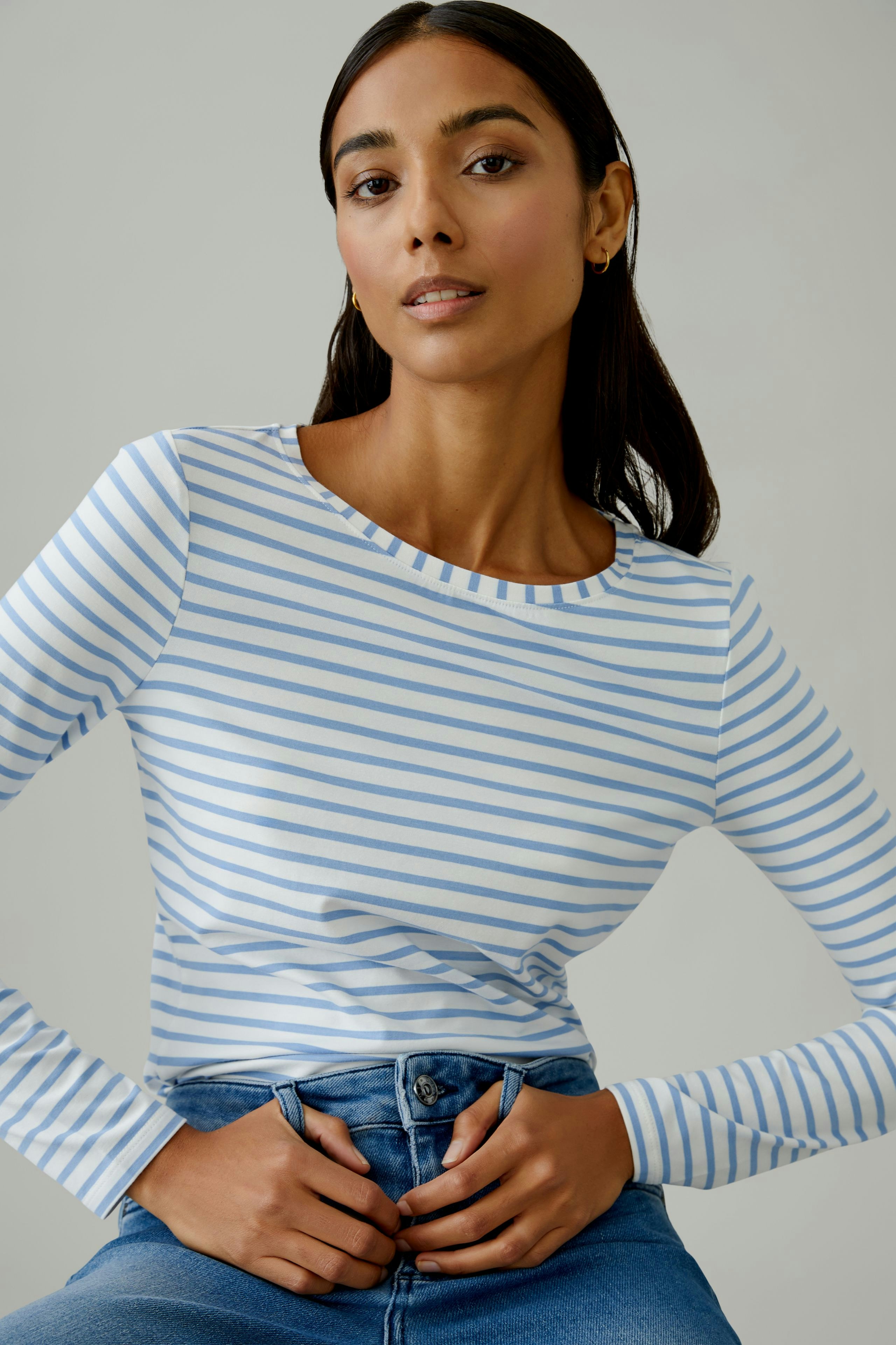 Casual long-sleeve shirt: Woman in a striped top with blue and white lines, paired with jeans.