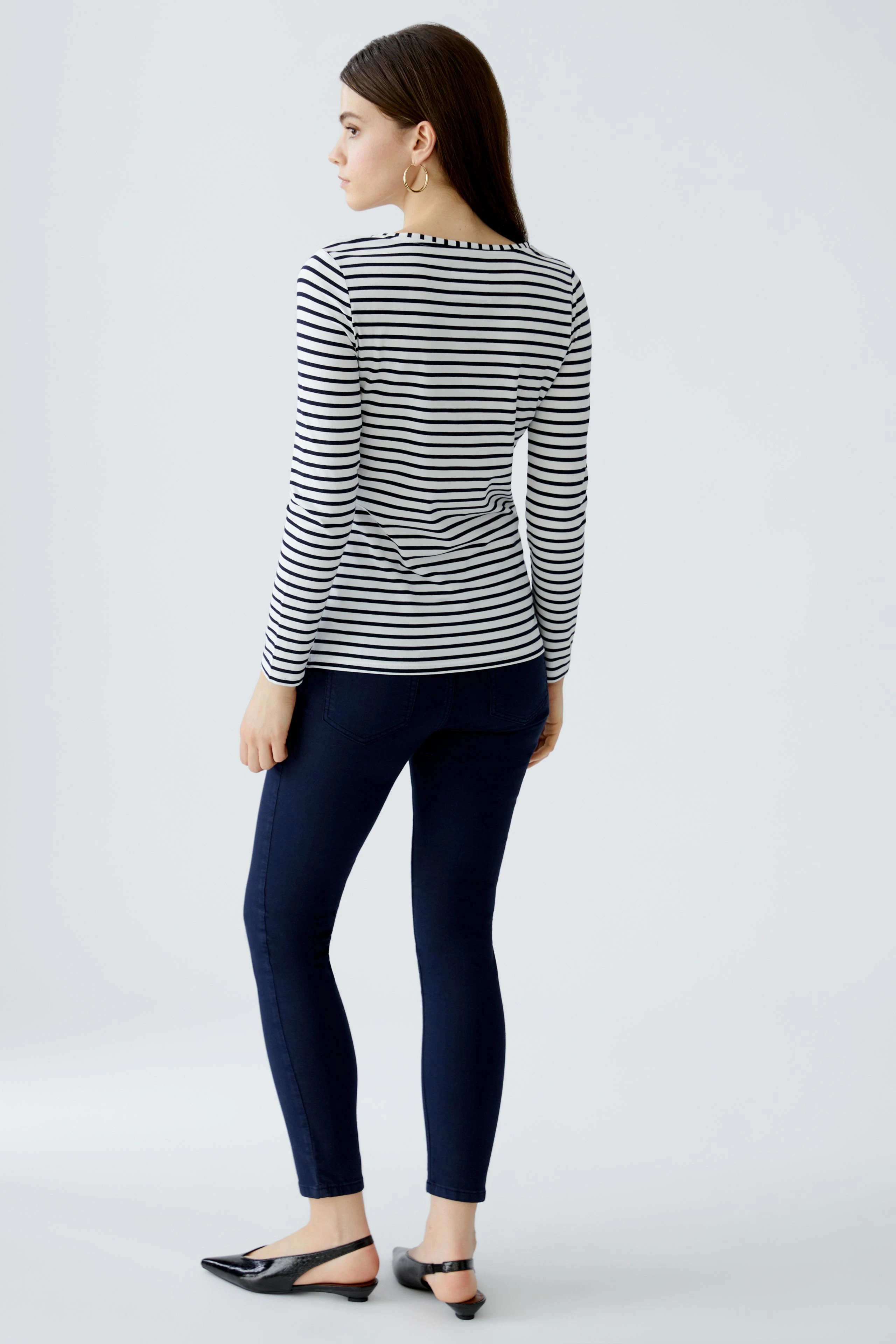 Damen Langarmshirt: Frau in gestreiftem Shirt mit Rundhalsausschnitt und schmalen Jeans von hinten.
