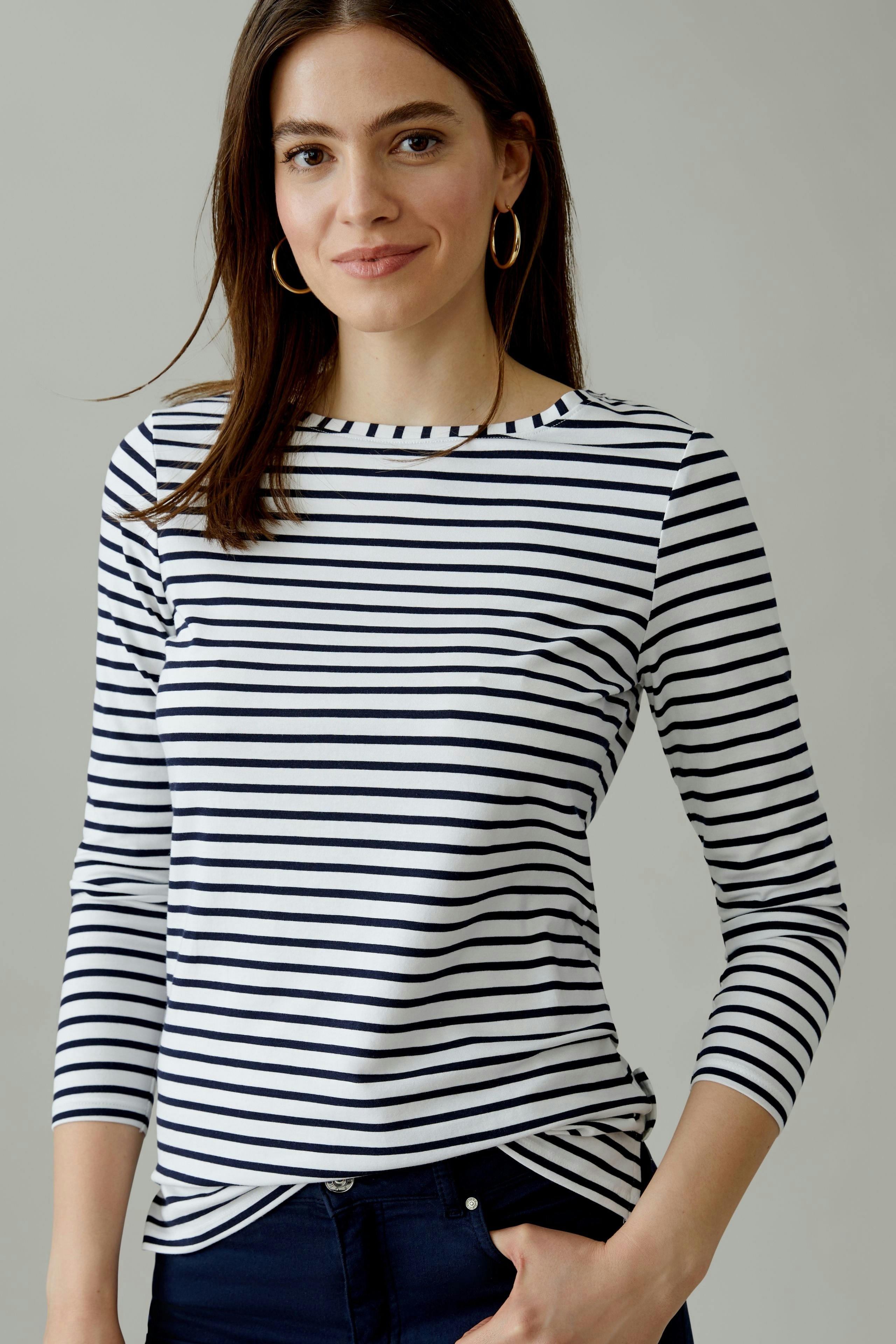 Casual women's long-sleeve shirt: Woman in a striped top with three-quarter sleeves, smiling confidently.