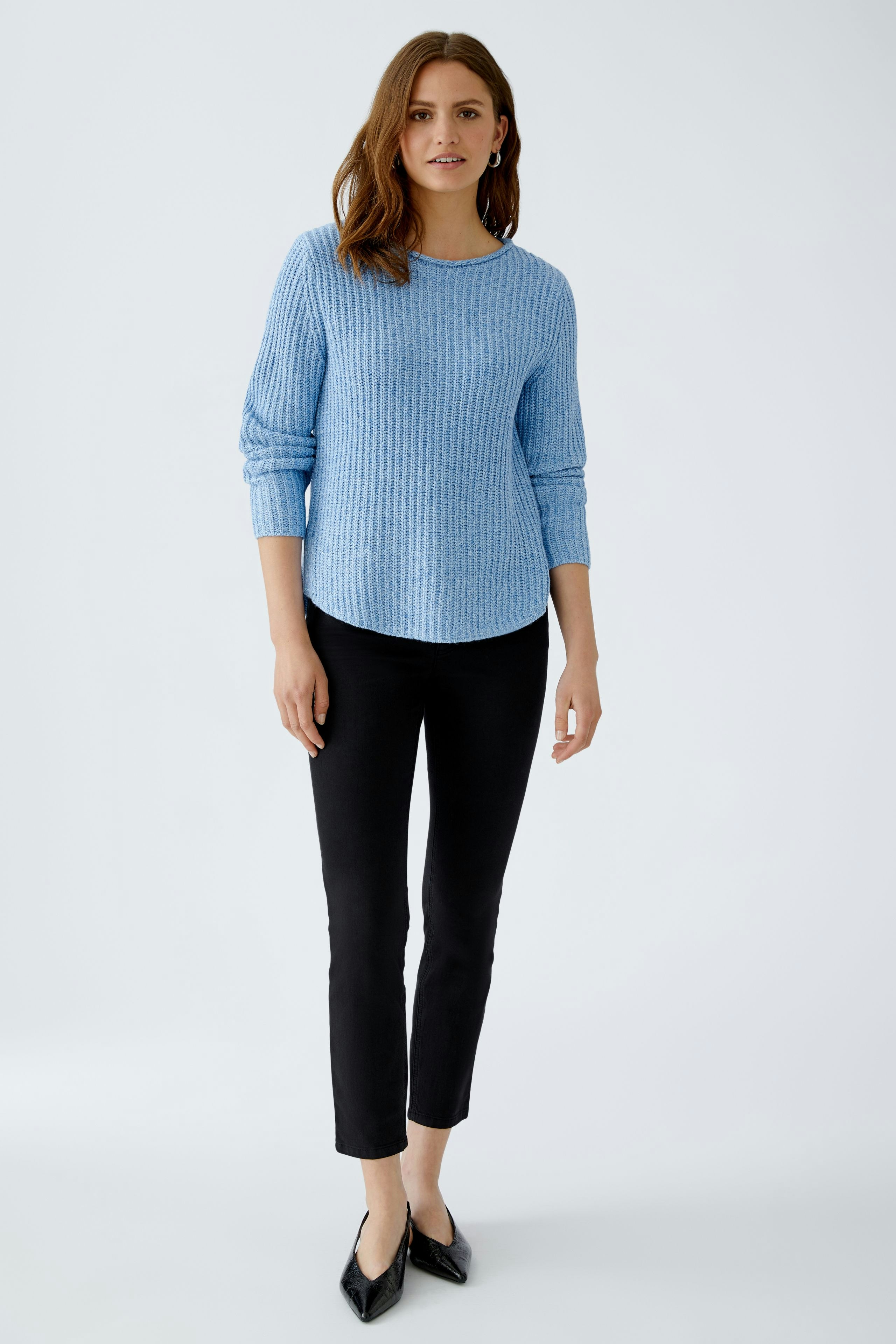 Modern women's pullover: A woman in a light blue ribbed pullover paired with white pants.