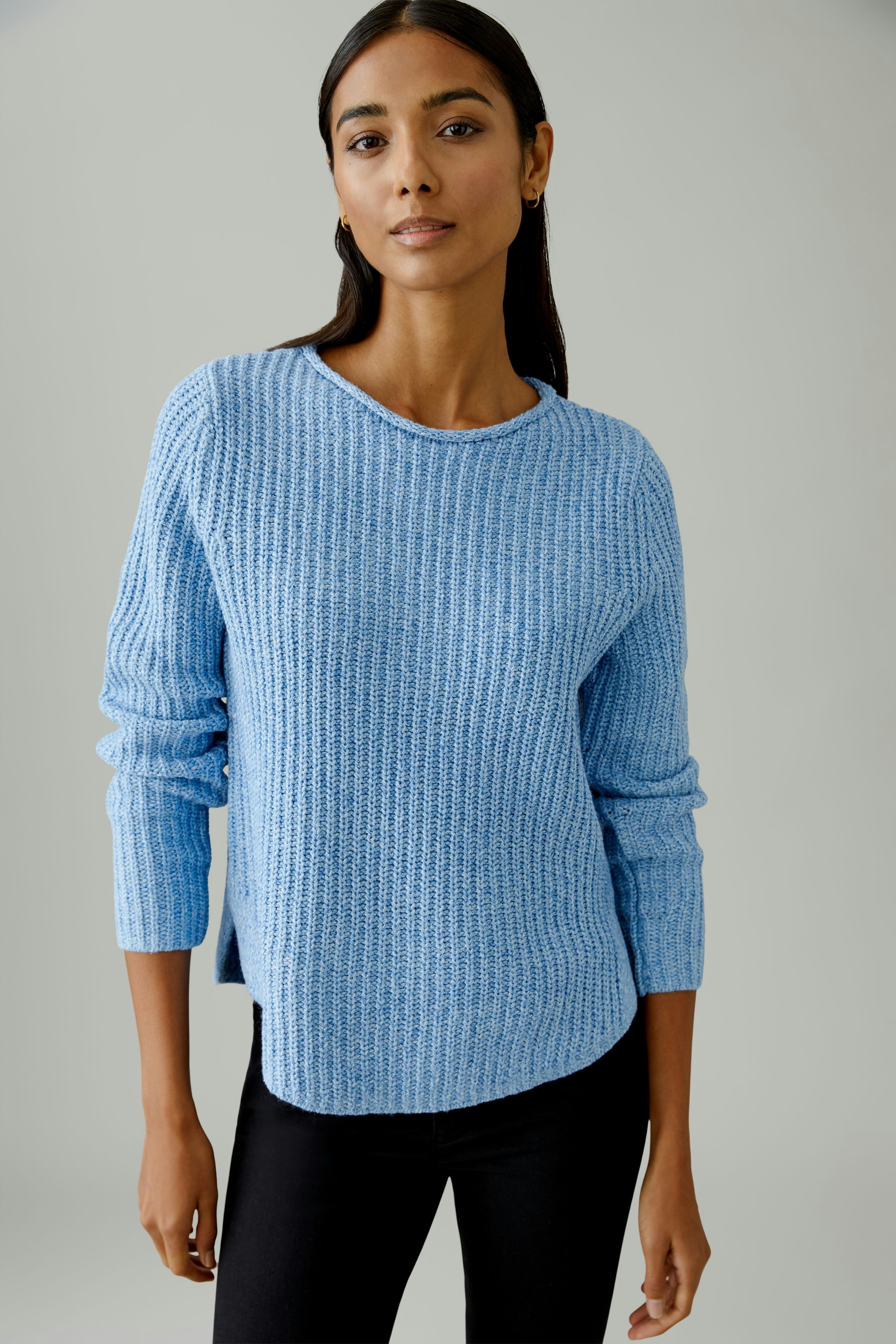 Casual women's pullover: Woman in a light blue textured pullover with long sleeves, paired with black pants.