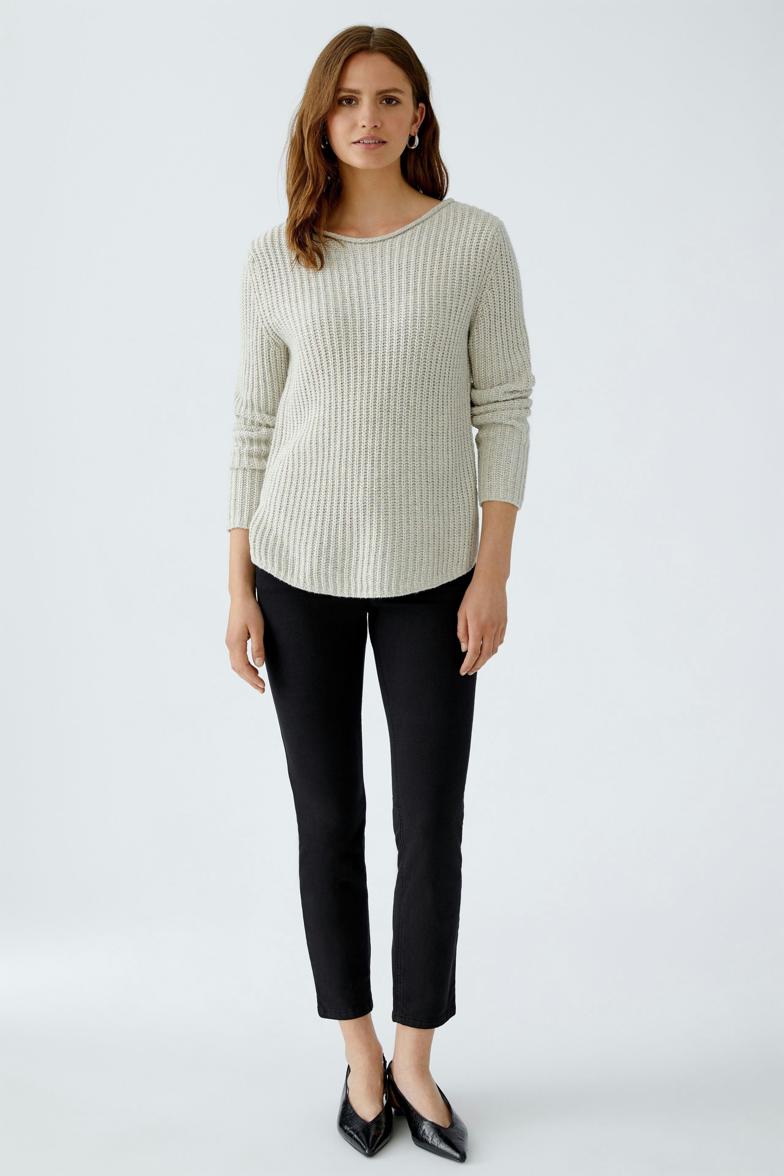 Casual women's pullover: A woman in a light ribbed pullover paired with black pants, standing confidently.