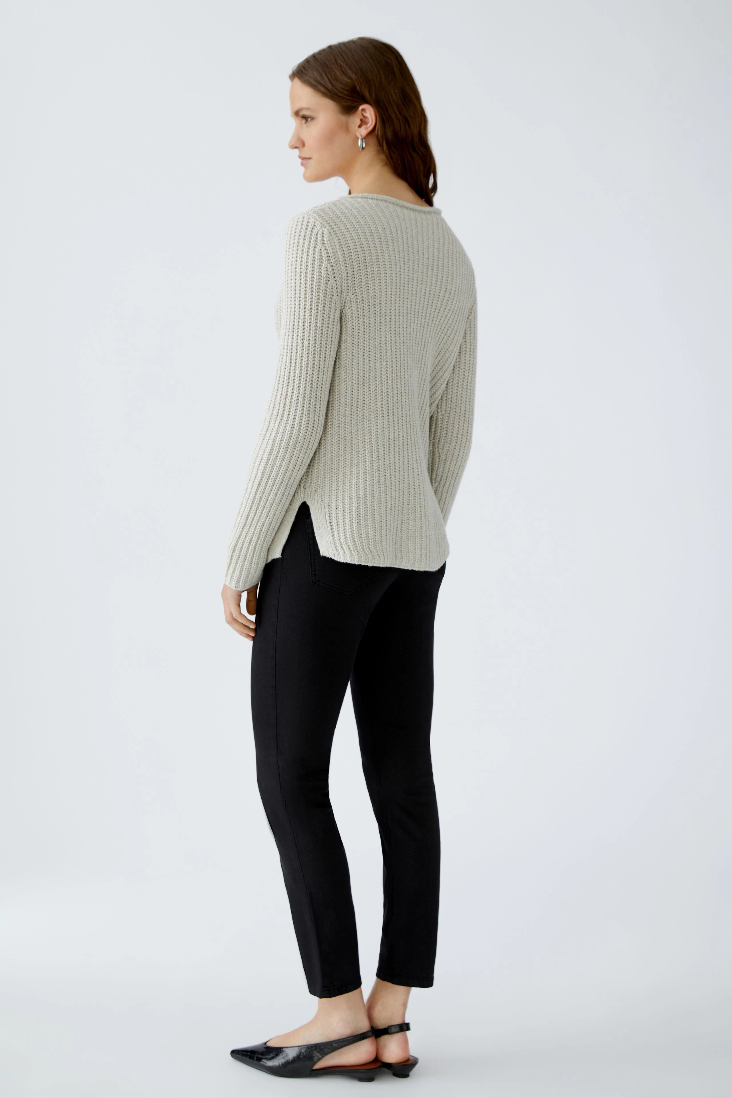 Casual women's pullover: A woman in a light gray ribbed pullover with a relaxed fit and side slits.