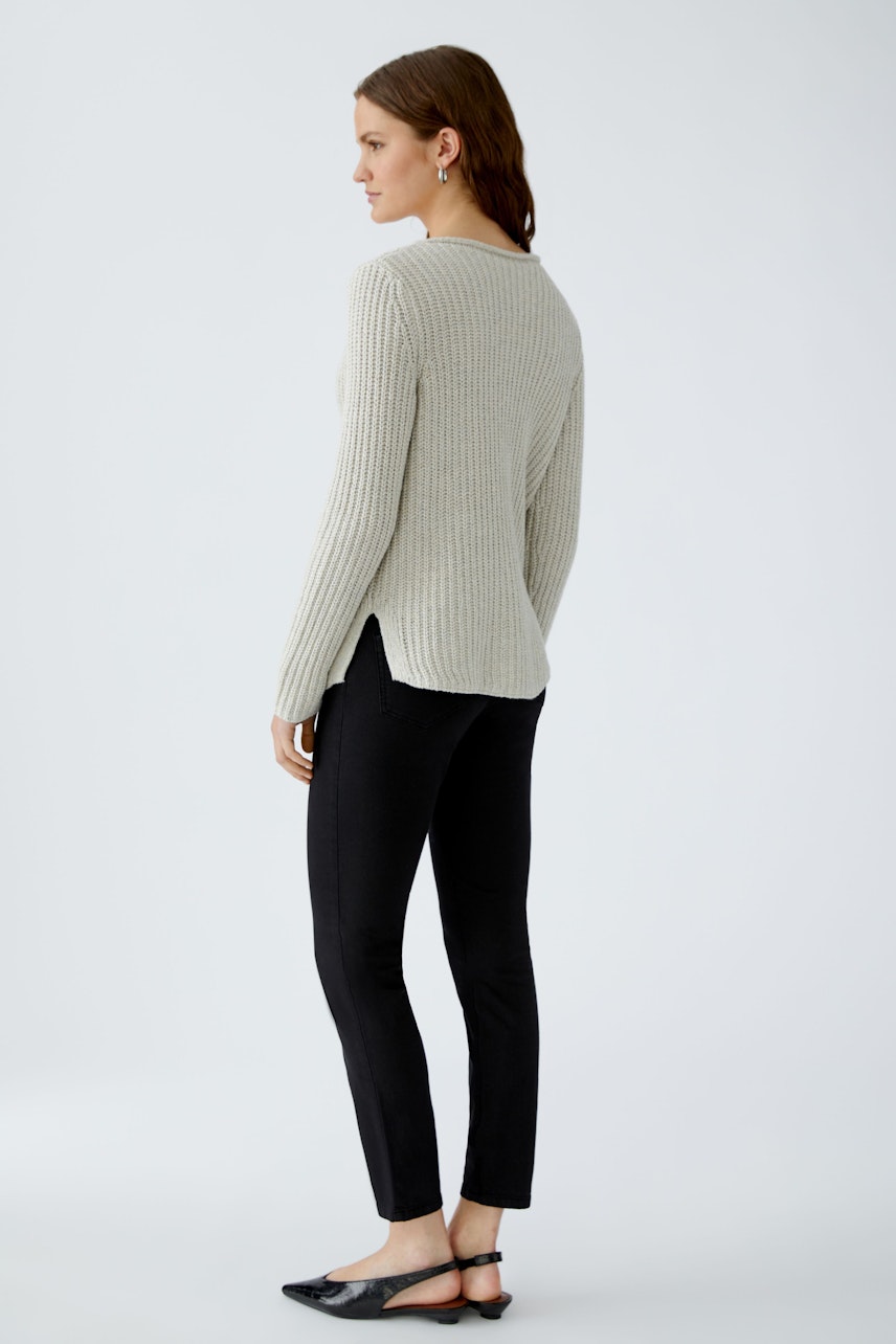 Damen-Pullover: Frau in grauem, geripptem Pullover mit seitlichen Schlitzen und schmalen Hosen.