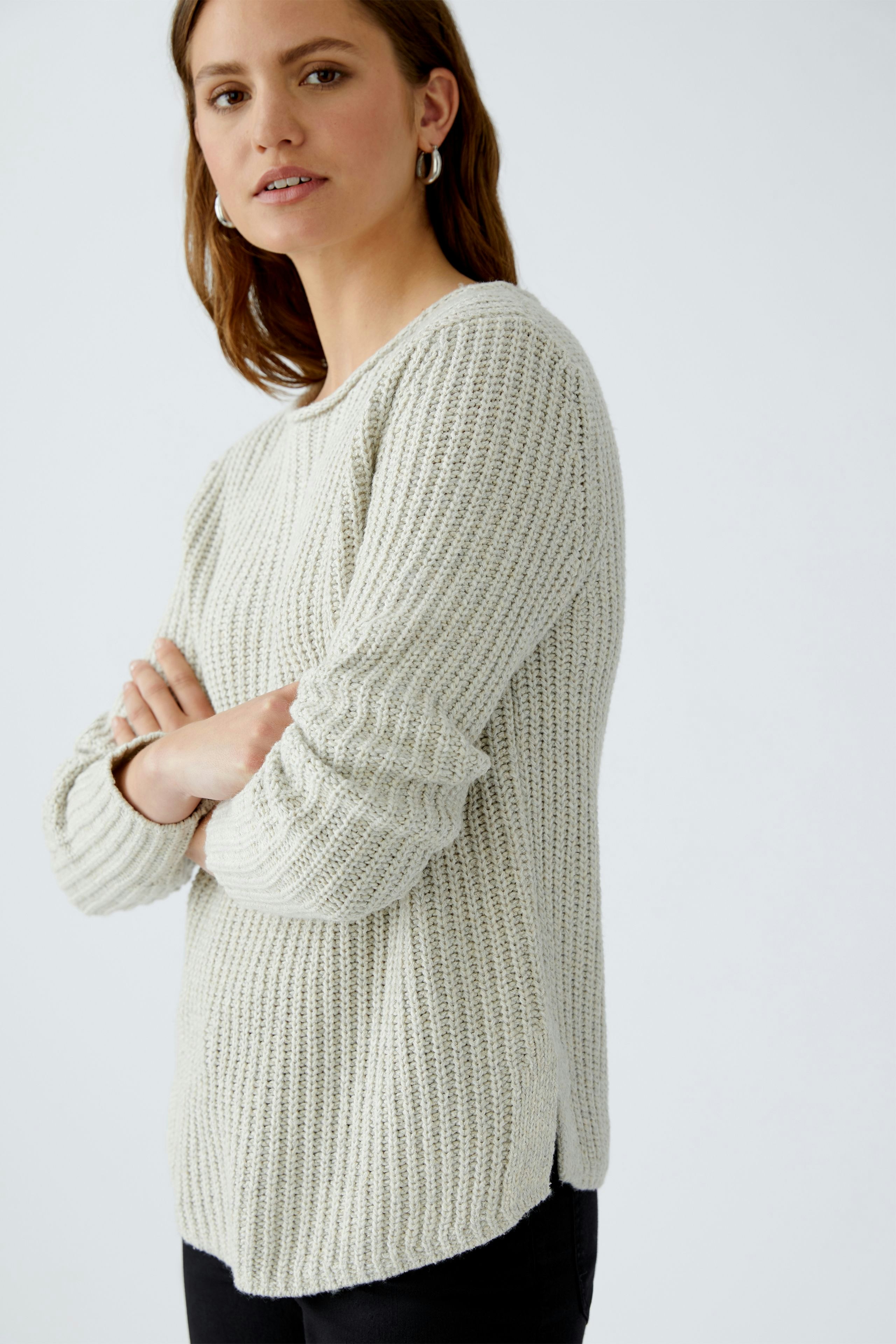 Casual women's pullover: A woman in a light knitted pullover with a relaxed fit and side slits.