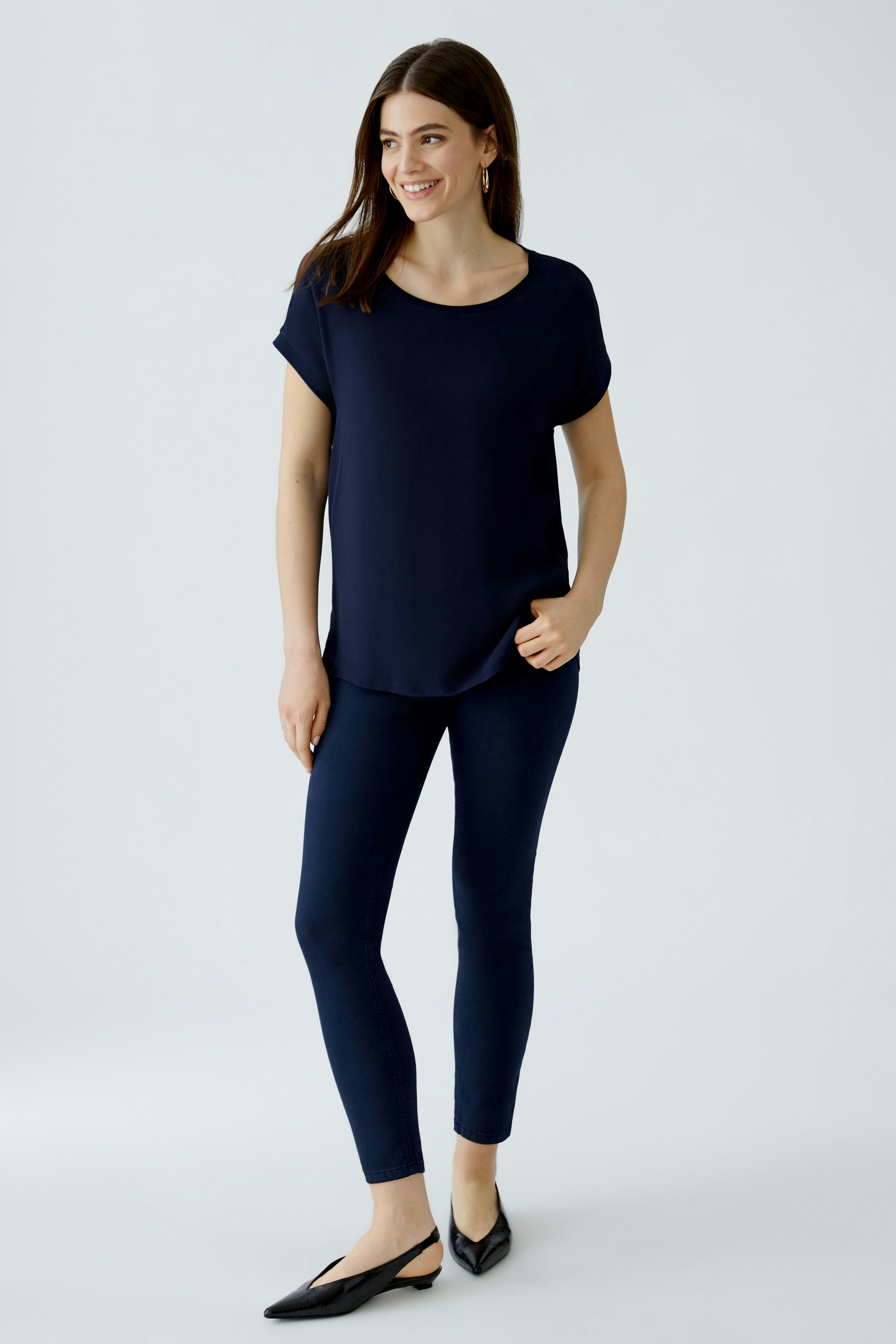 Bequeme Blusenshirt für Damen: Frau in navyfarbener Bluse und schmalen Hosen, lächelt entspannt.