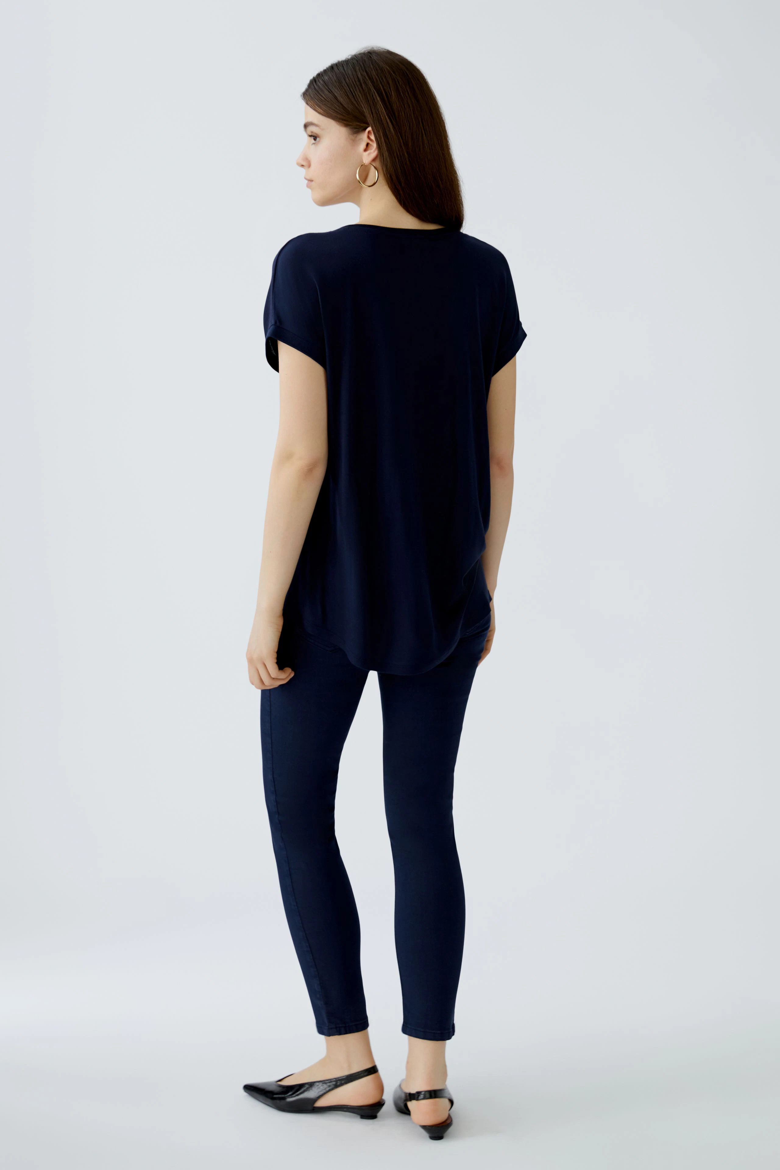 Casual women's blouse shirt: A woman in a navy blue top paired with fitted jeans, showcasing a relaxed style.