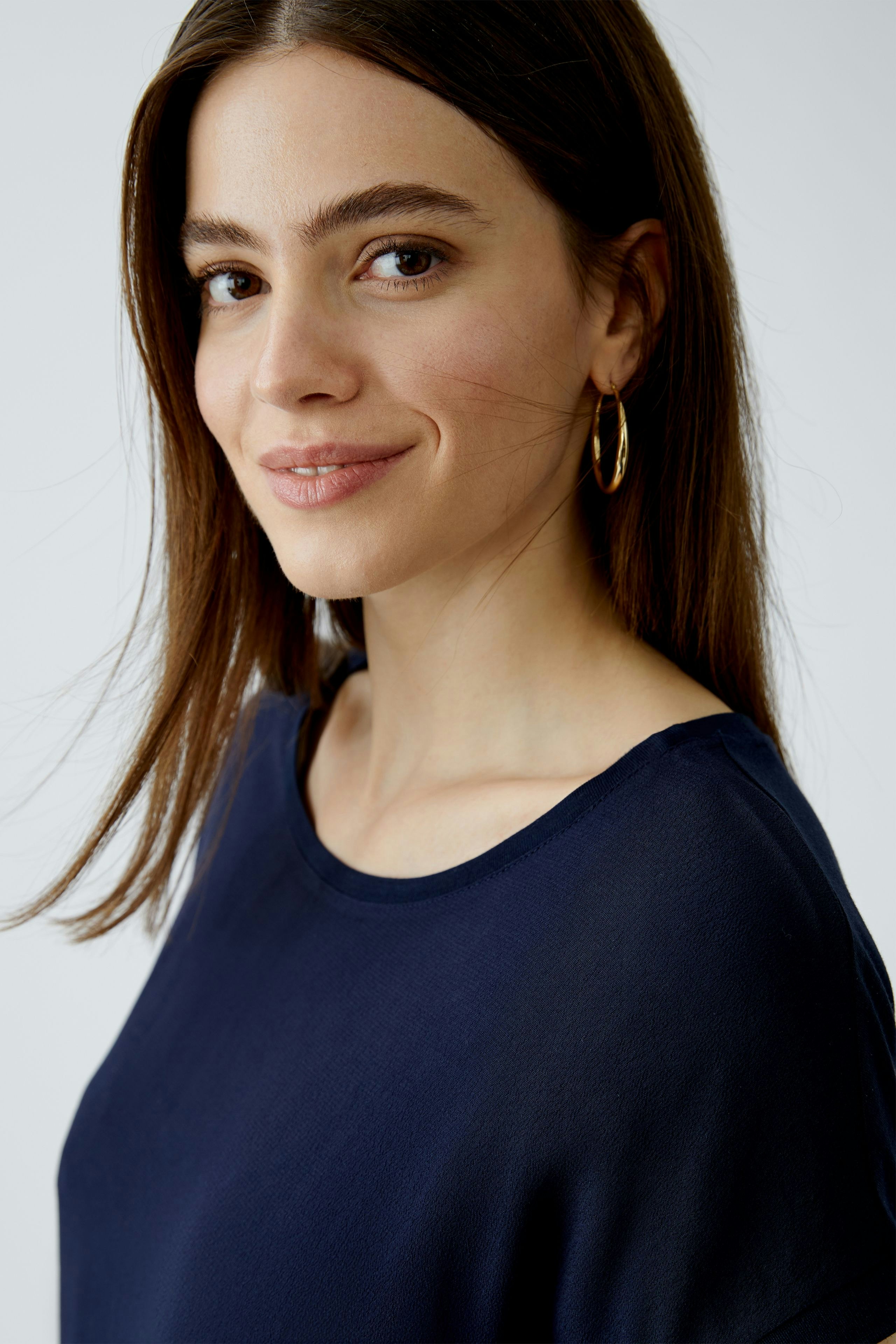 Damen Blusenshirt: Junge Frau trägt ein navyfarbenes, lässiges Blusenshirt mit Rundhalsausschnitt.