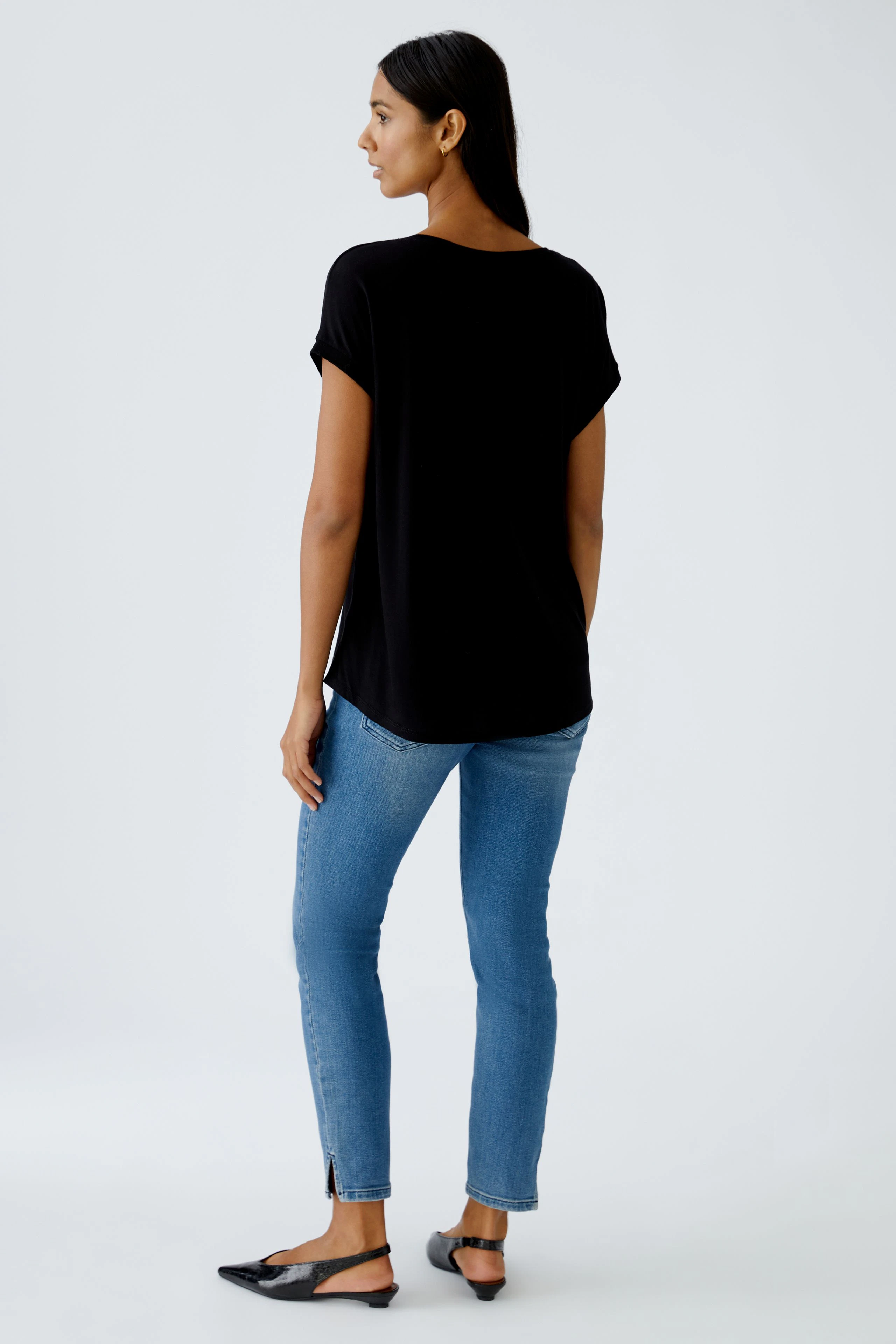 Bequemes Blusenshirt: Frau in schwarzem Shirt mit lässigem Schnitt und kurzen Ärmeln, kombiniert mit Jeans.