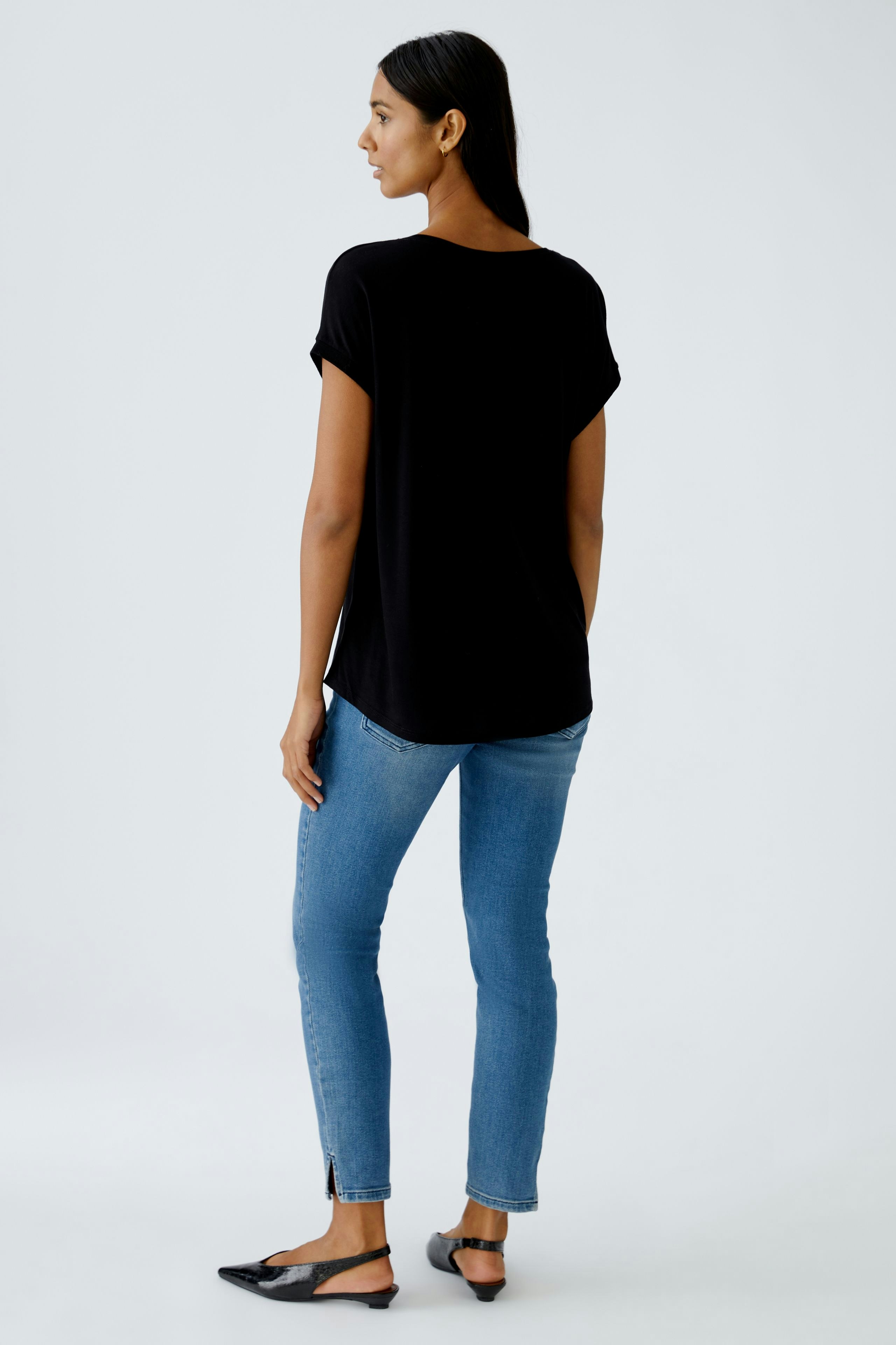 Bequemes Blusenshirt: Frau in schwarzem Shirt mit lässigem Schnitt und kurzen Ärmeln, kombiniert mit Jeans.