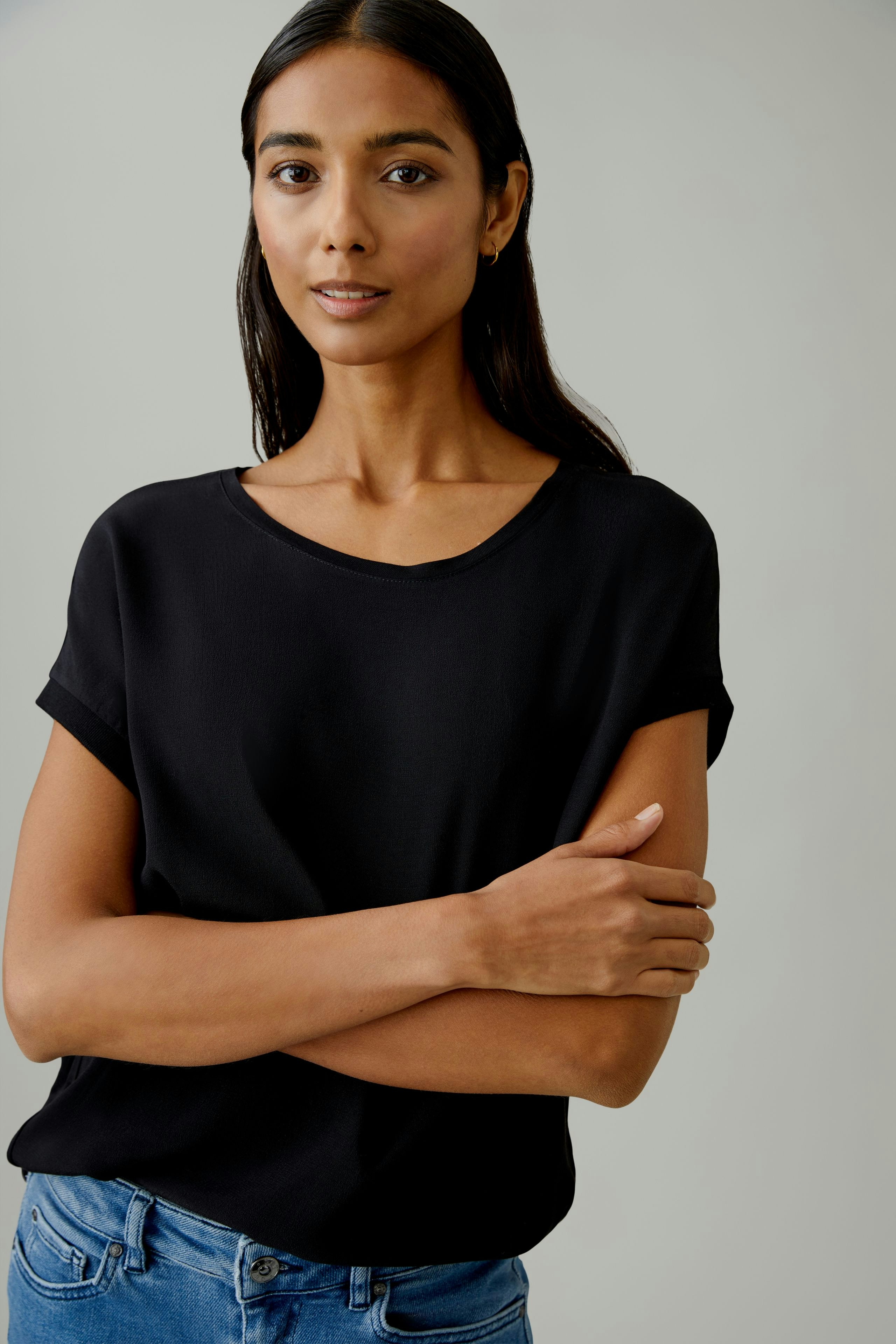 Schwarzes Blusenshirt: Junge Frau trägt ein schlichtes, schwarzes Blusenshirt mit lässigem Schnitt.