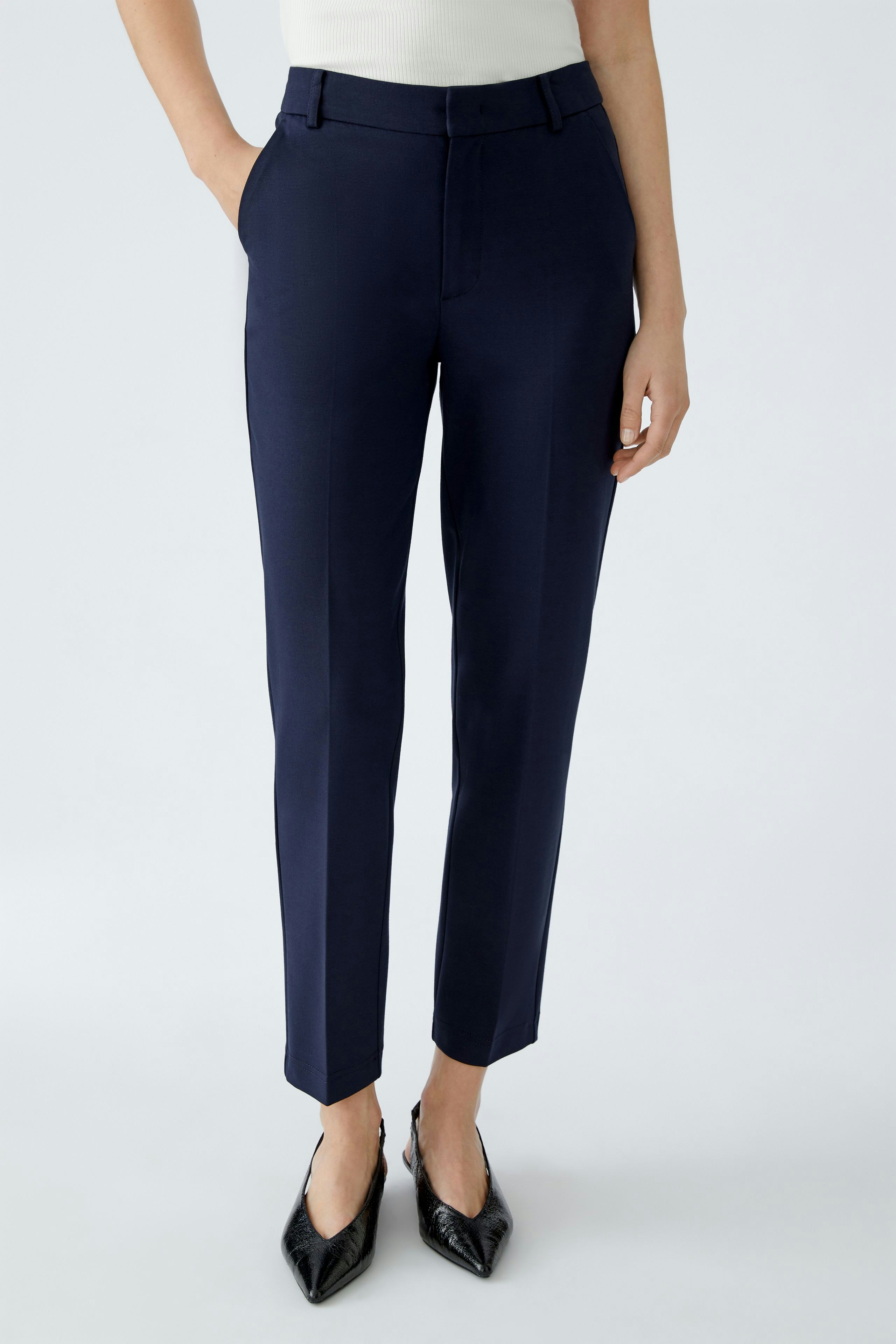 Modern women's trousers: A woman in navy pants with a tailored fit, paired with stylish heels.