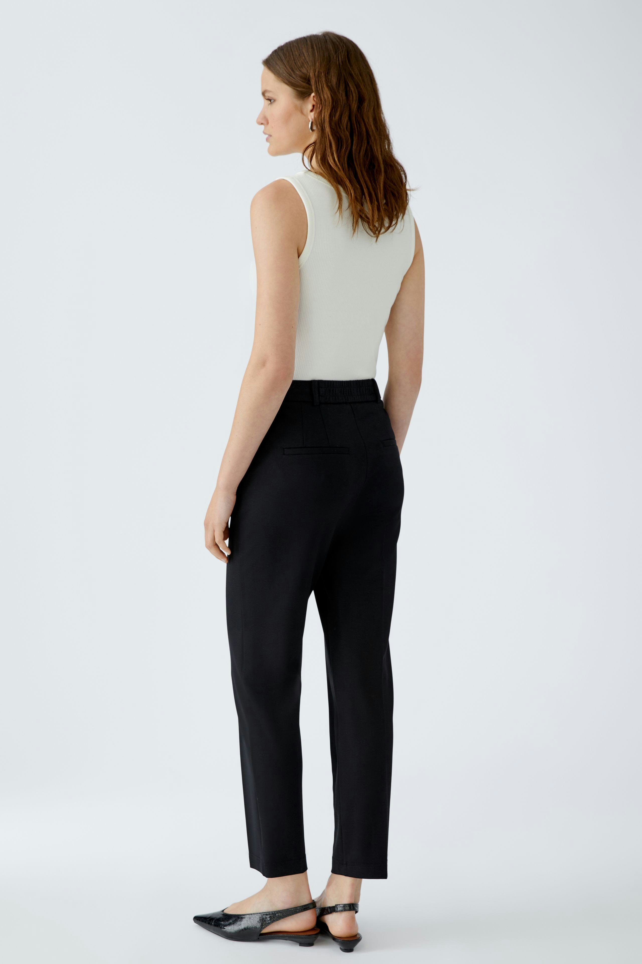 Chic women's trousers: A woman in black trousers with a fitted top, showcasing a modern silhouette.