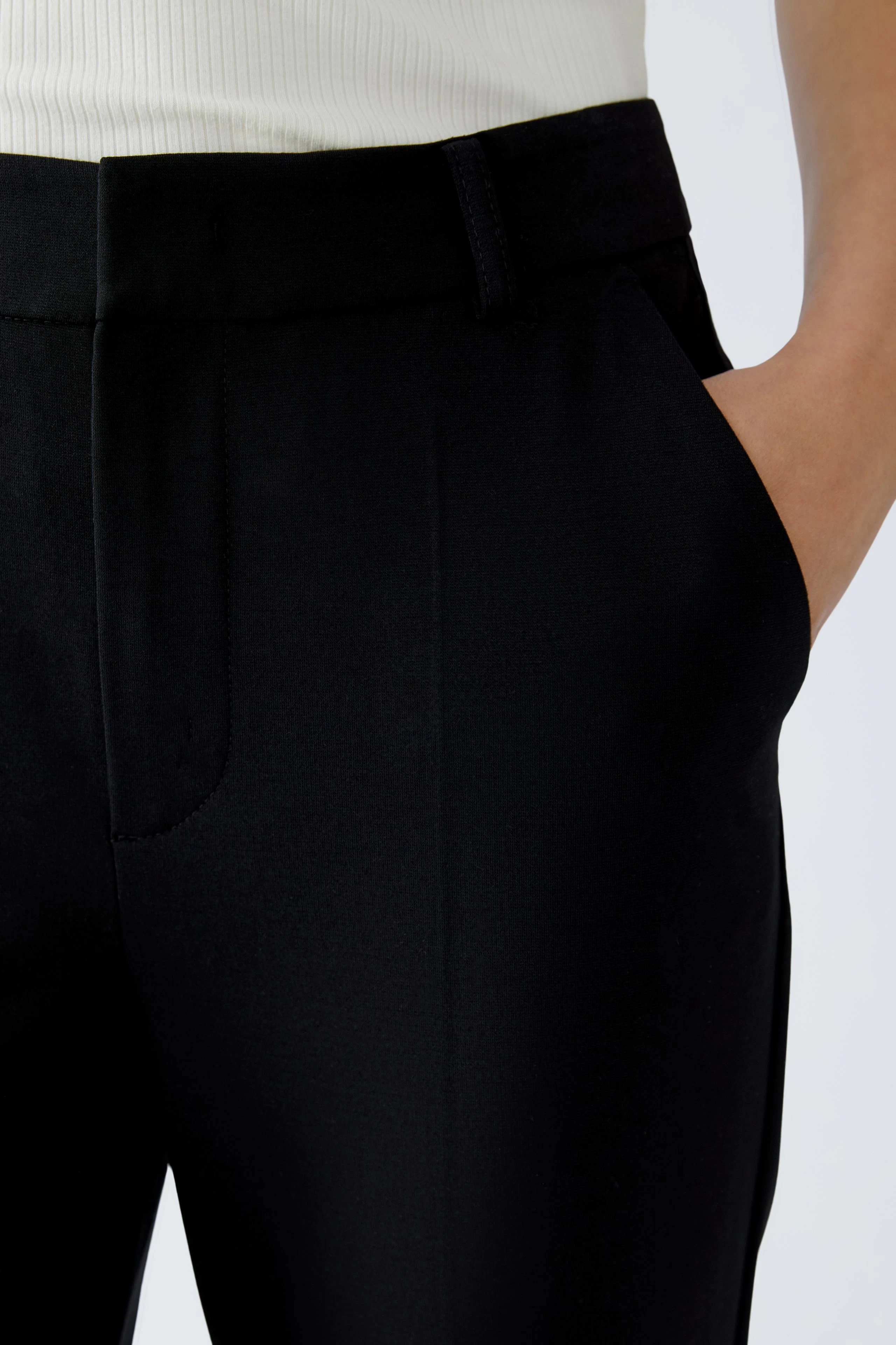 Casual women's pants: Close-up of a woman wearing black pants with a sleek design and side pockets.