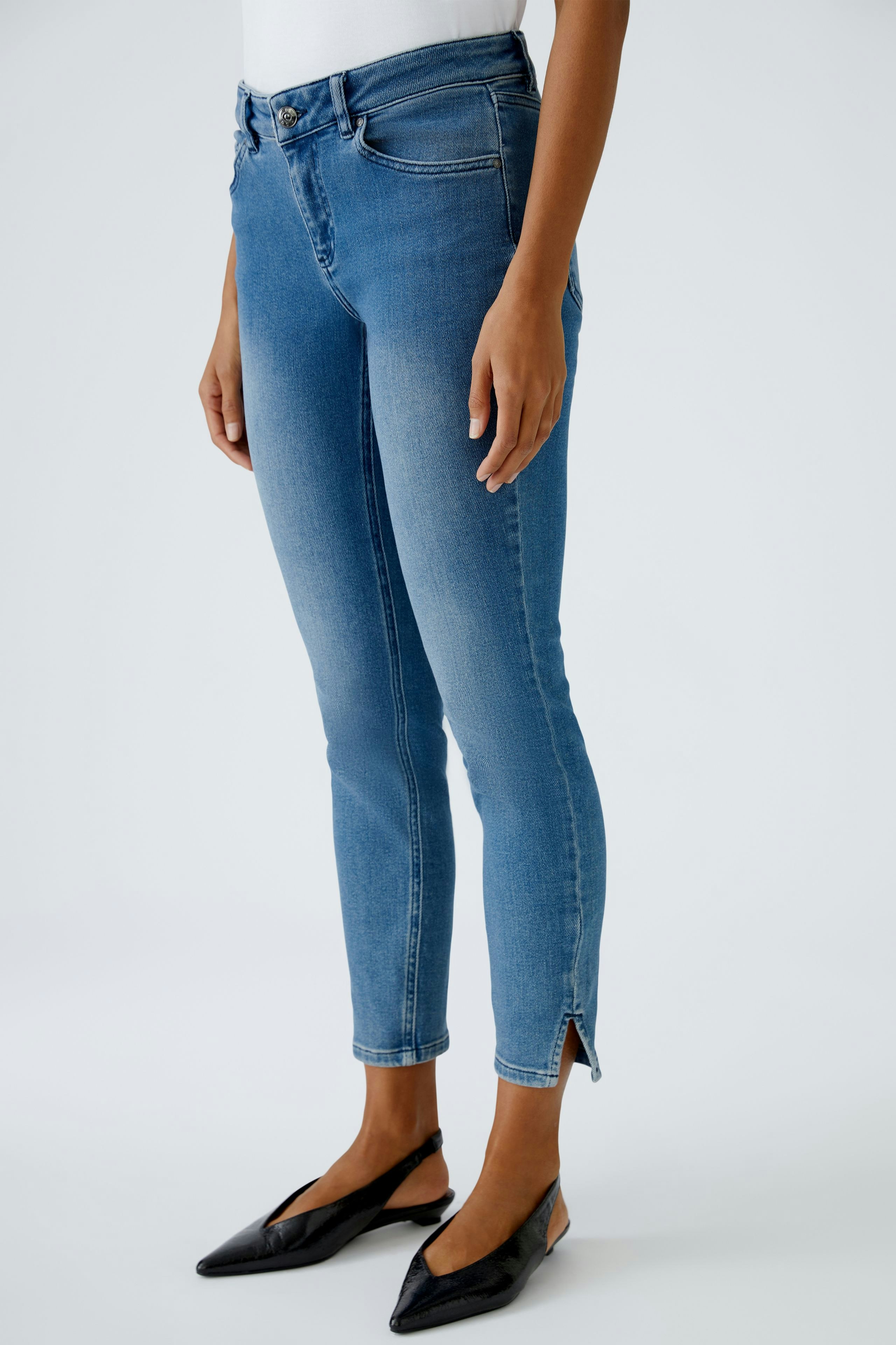 Damen Jeans Skinny: Frau in blauen Skinny Jeans mit seitlichen Schlitzen und eleganten Schuhen.