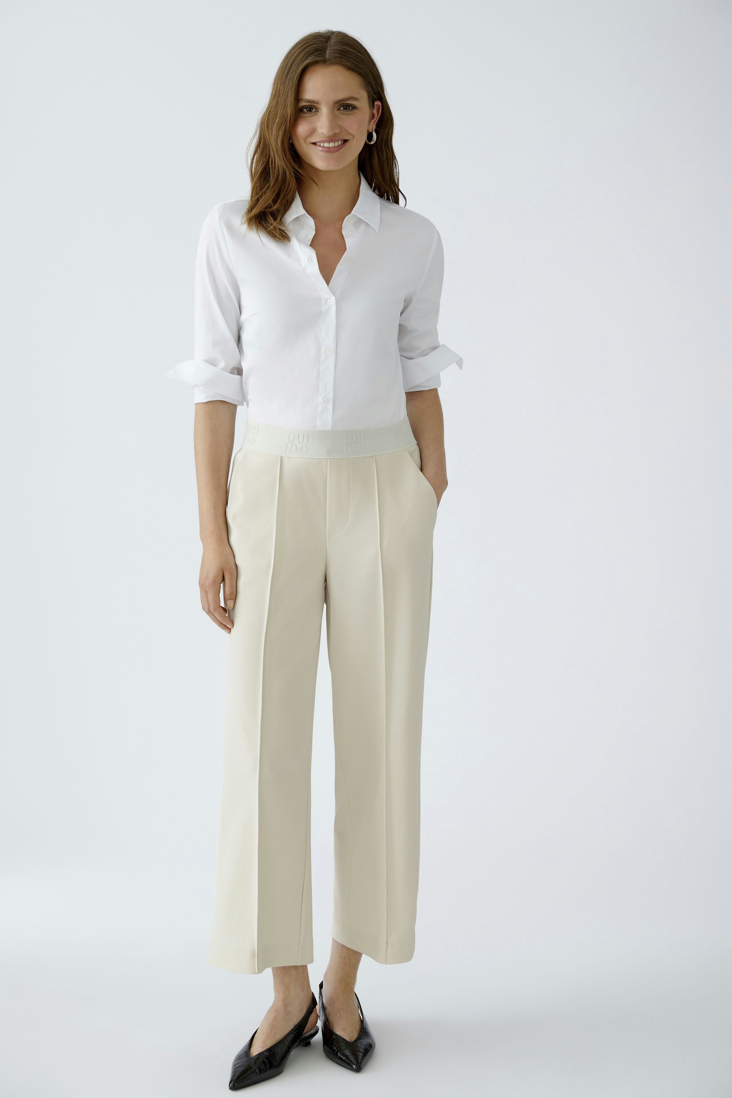 Chic culotte: Woman in cream culottes with a relaxed fit and a stylish waistband, paired with a white shirt.