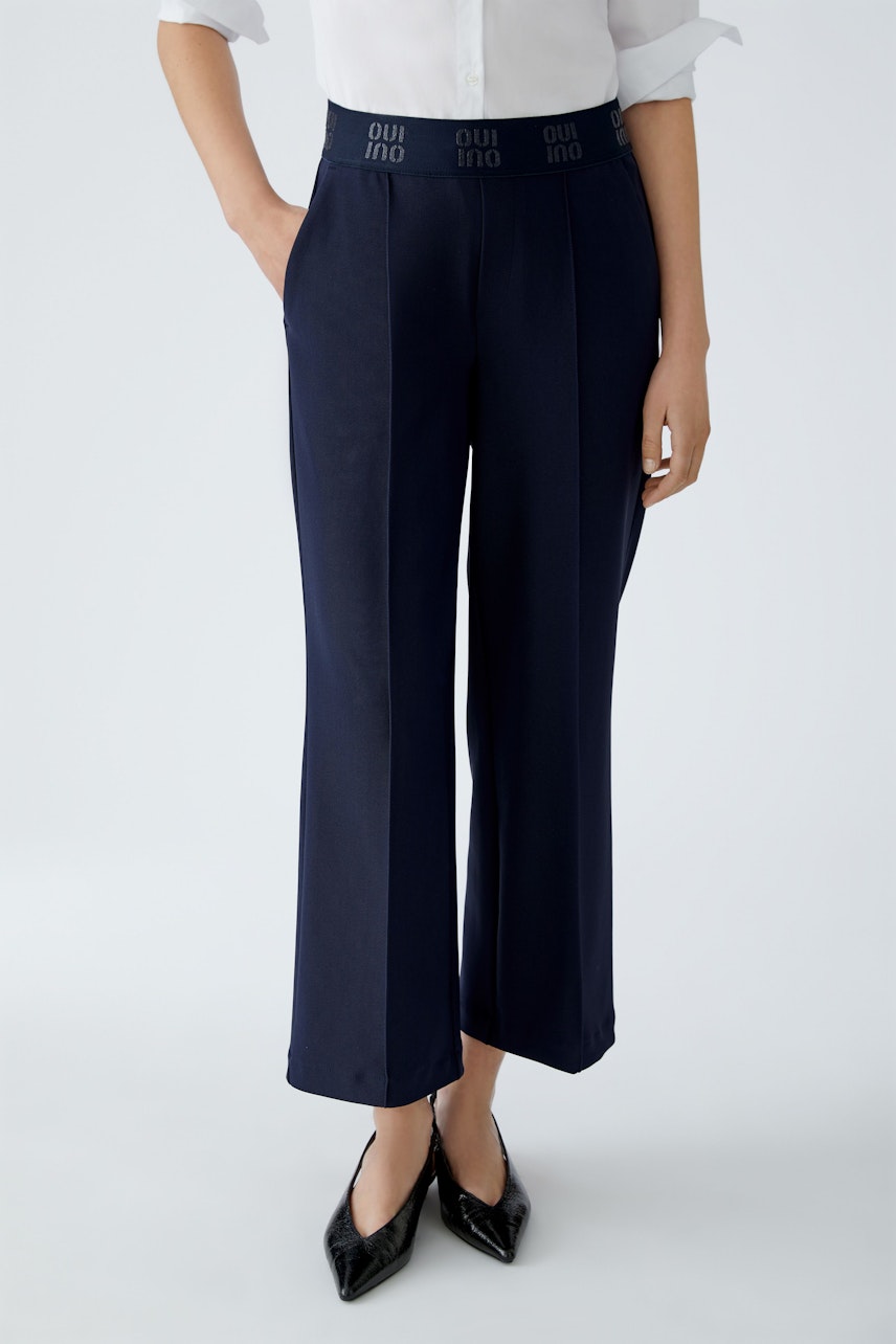 Modern culotte: Woman in navy wide-leg pants with a comfortable fit and stylish logo waistband.