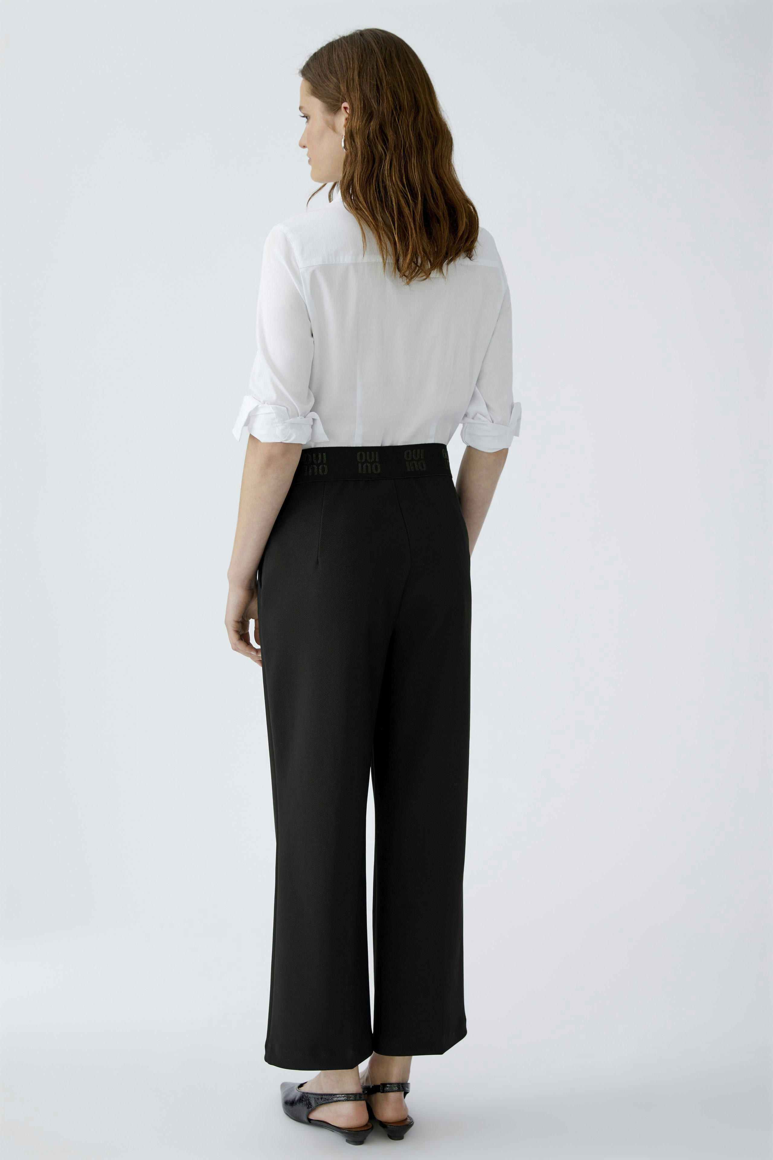 Stylish culotte: Woman in black wide-leg pants with a fitted waist, paired with a white shirt.