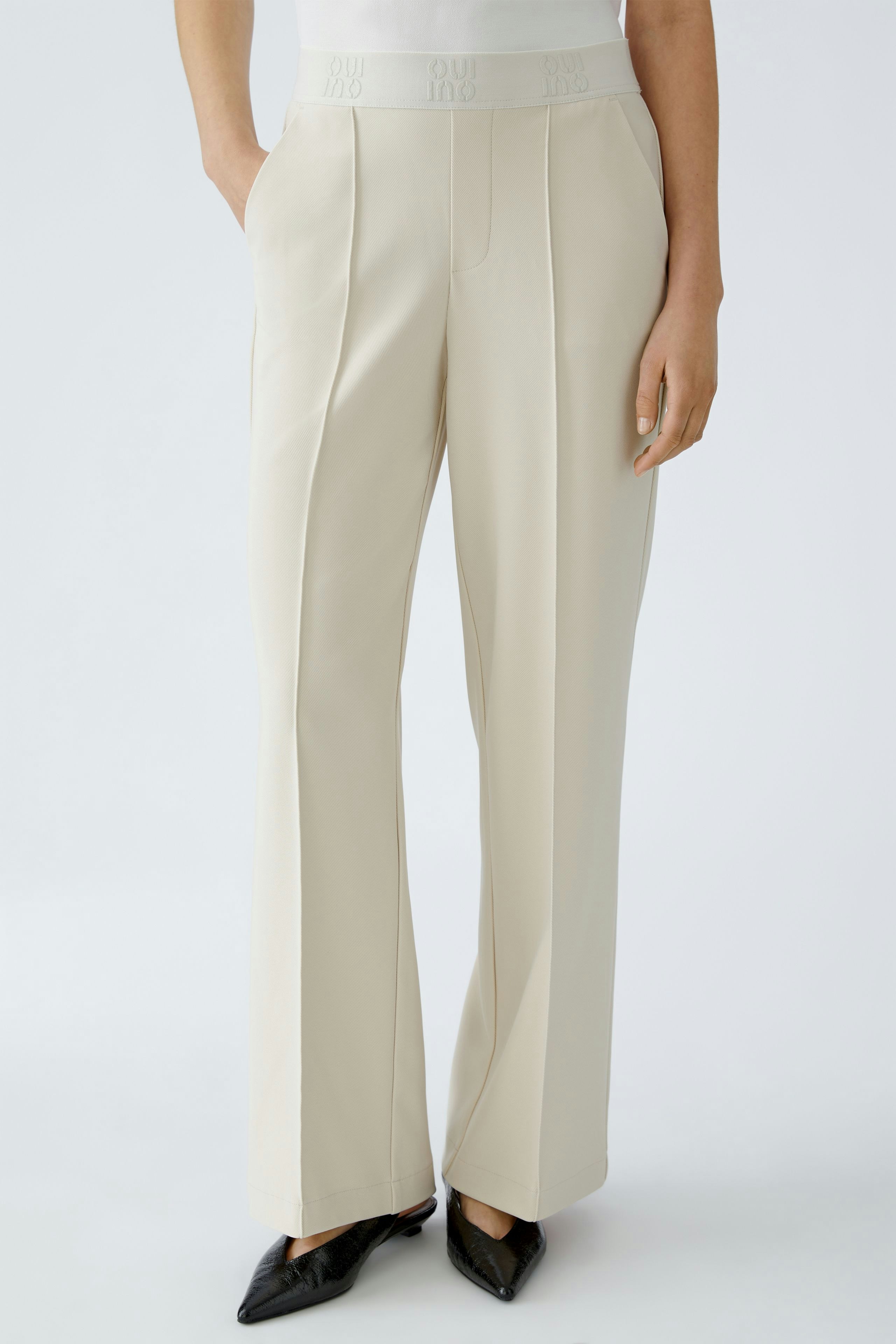 Modern women's trousers: A woman in light beige trousers with a comfortable waistband and stylish fit.