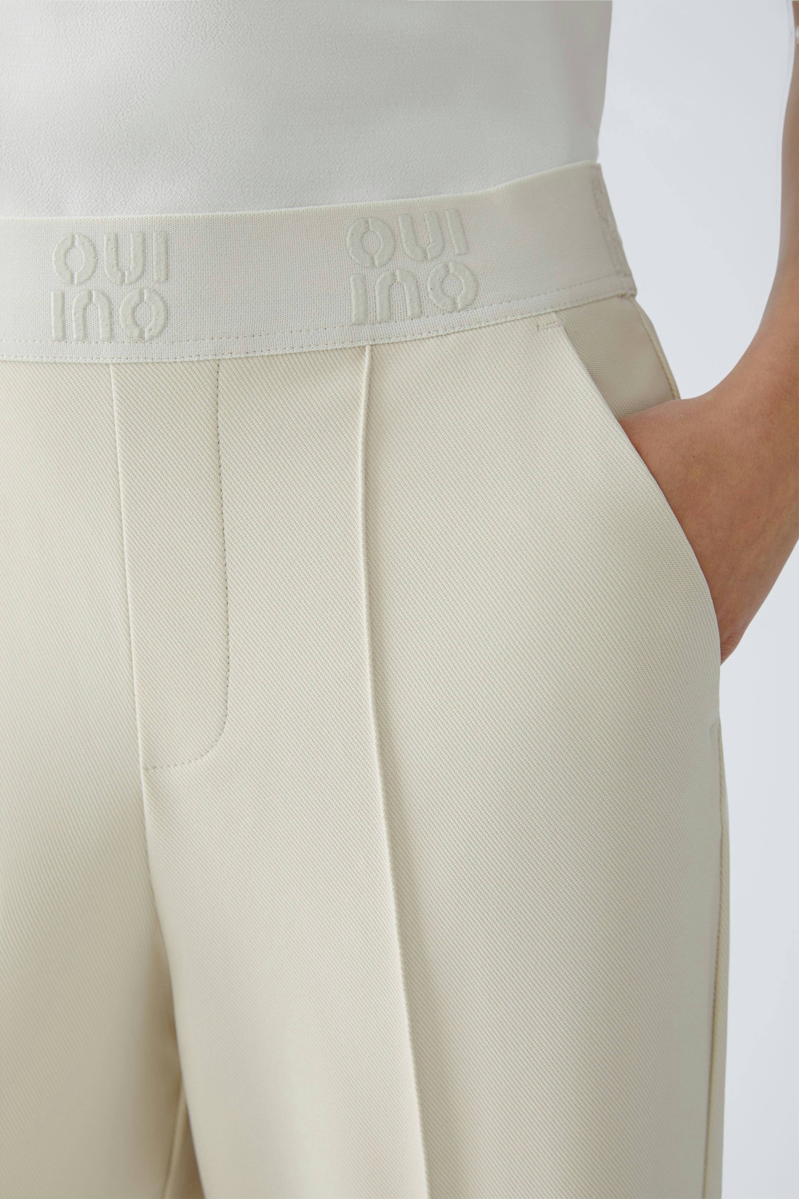Casual women's trousers: Close-up of a woman wearing light beige trousers with a comfortable waistband.