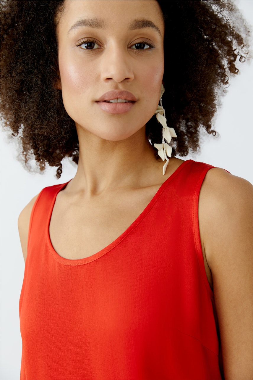 Casual women's top: Young woman in a vibrant red sleeveless top, showcasing a relaxed style.