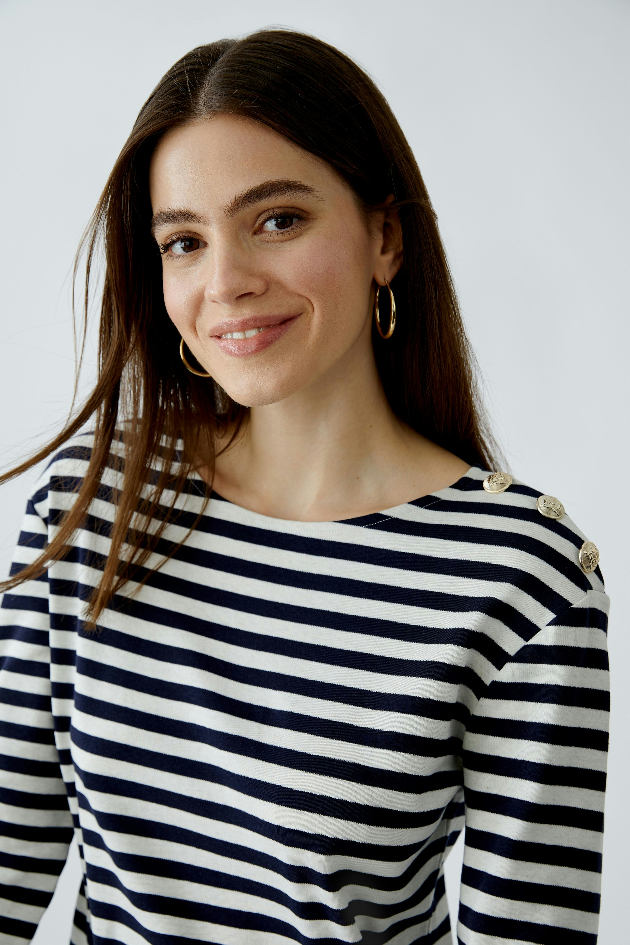 Stylish long-sleeve shirt: Woman in a striped pullover with button details, exuding casual elegance.