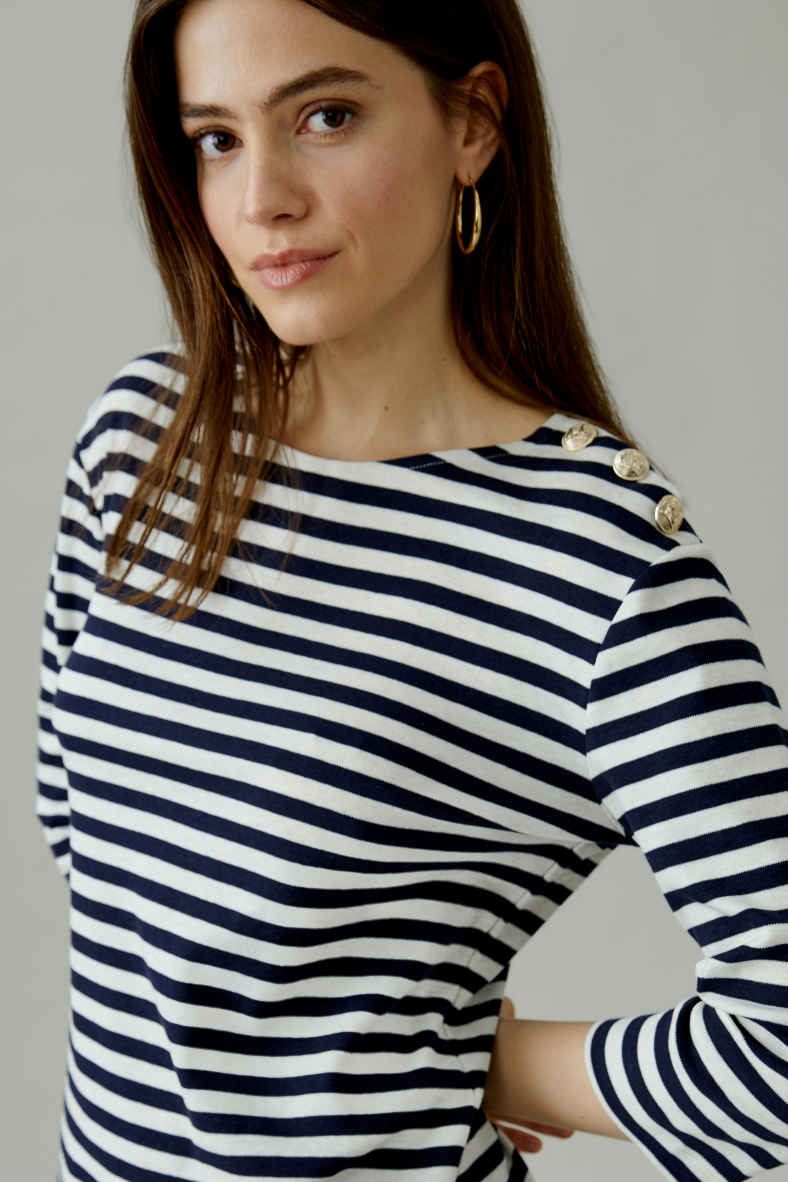 Casual women's long-sleeve shirt: Woman in a navy and white striped top with button details.