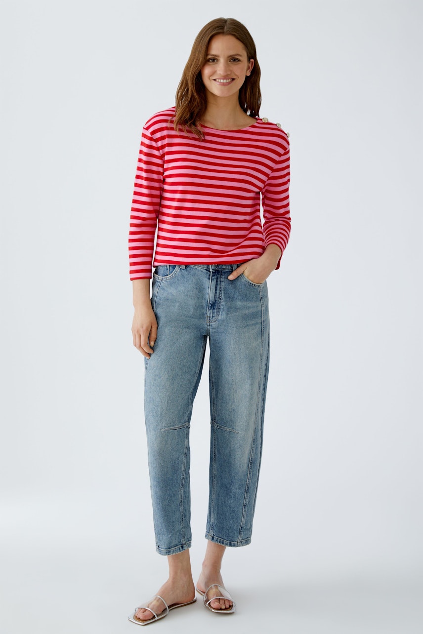 Casual long-sleeve shirt: Woman in a red and white striped pullover paired with relaxed-fit jeans.