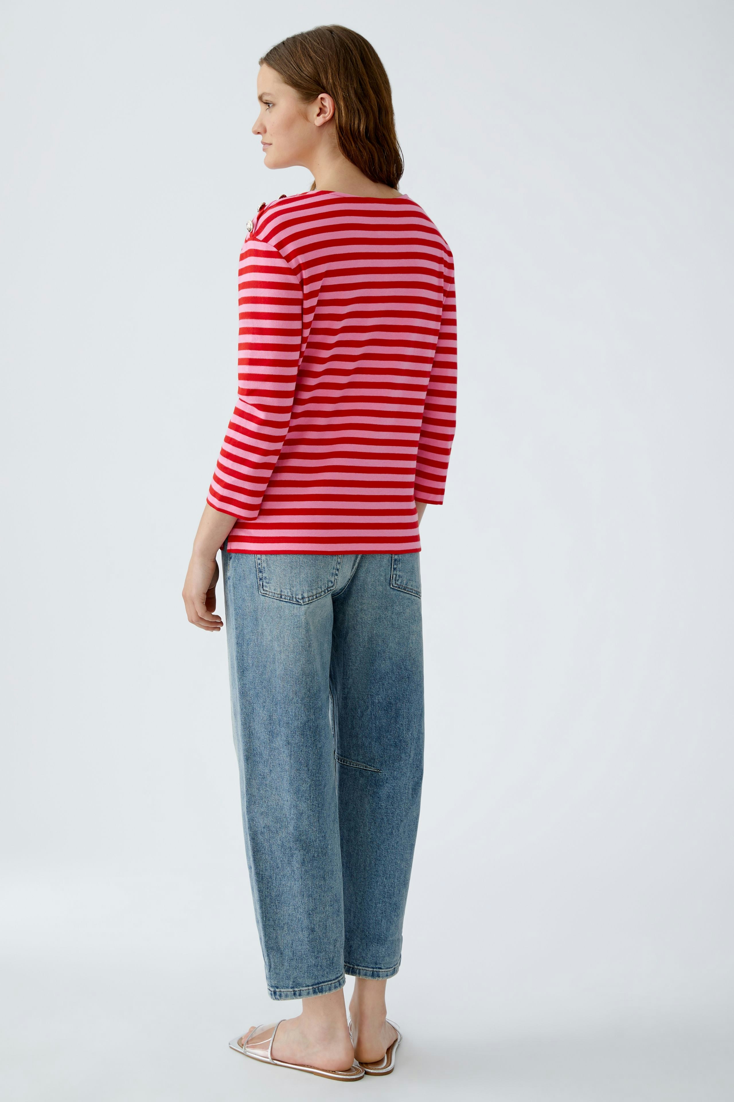 Damen Langarmshirt: Frau in rot-weiß gestreiftem Shirt mit 3/4-Ärmeln und lässigen Jeans.