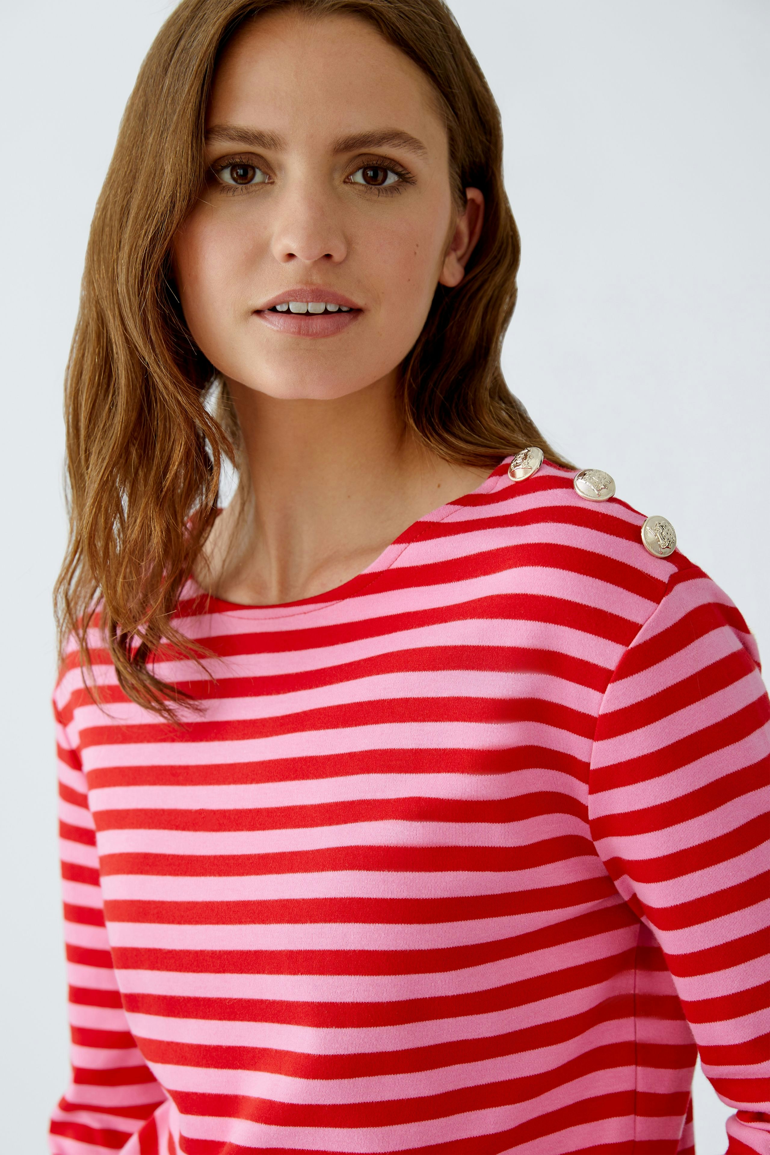 Langarmshirt: Junge Frau in gestreiftem Shirt mit Knöpfen am Ausschnitt lächelt freundlich.