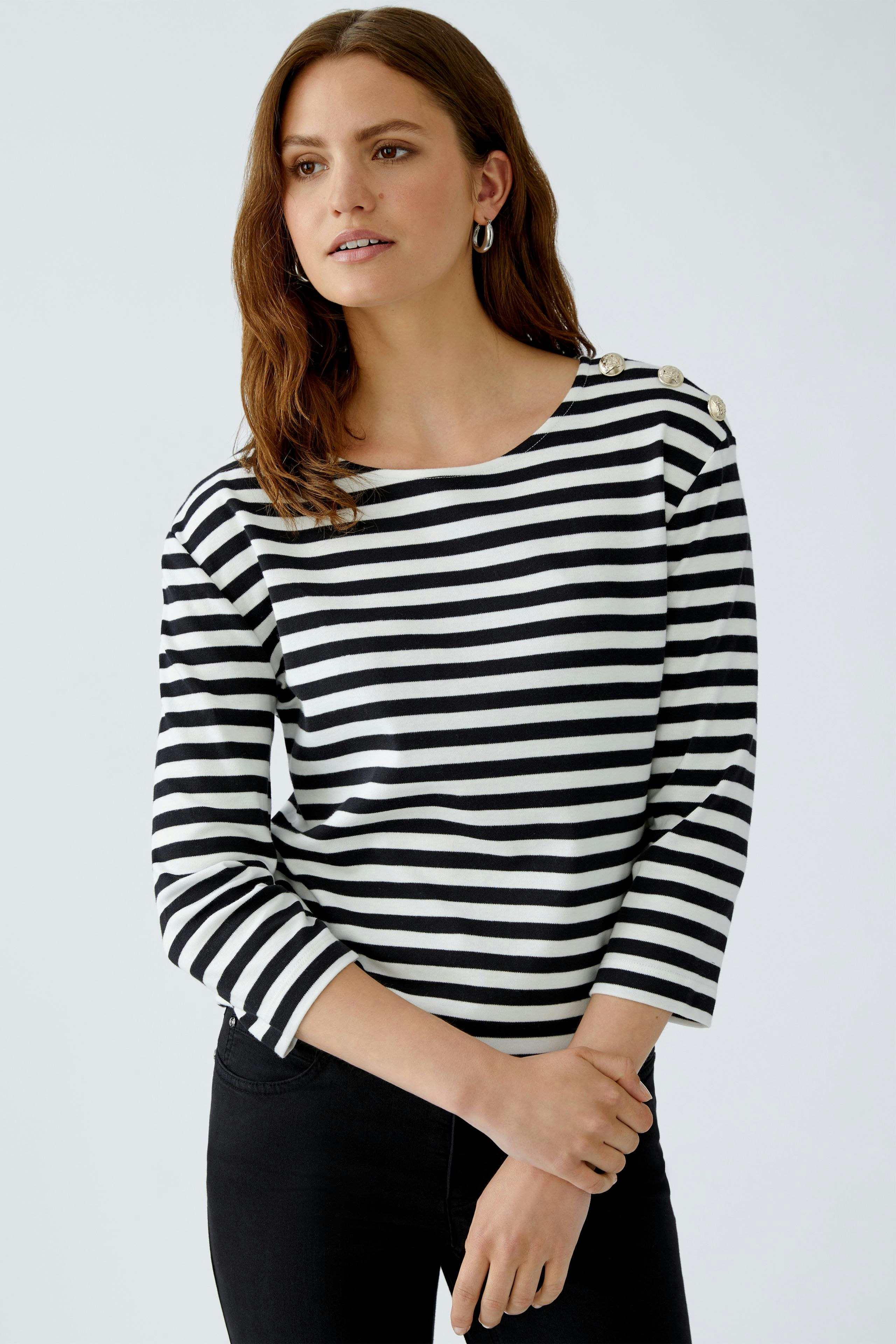 Stylish long-sleeve shirt: Woman in a black and white striped pullover with decorative buttons.