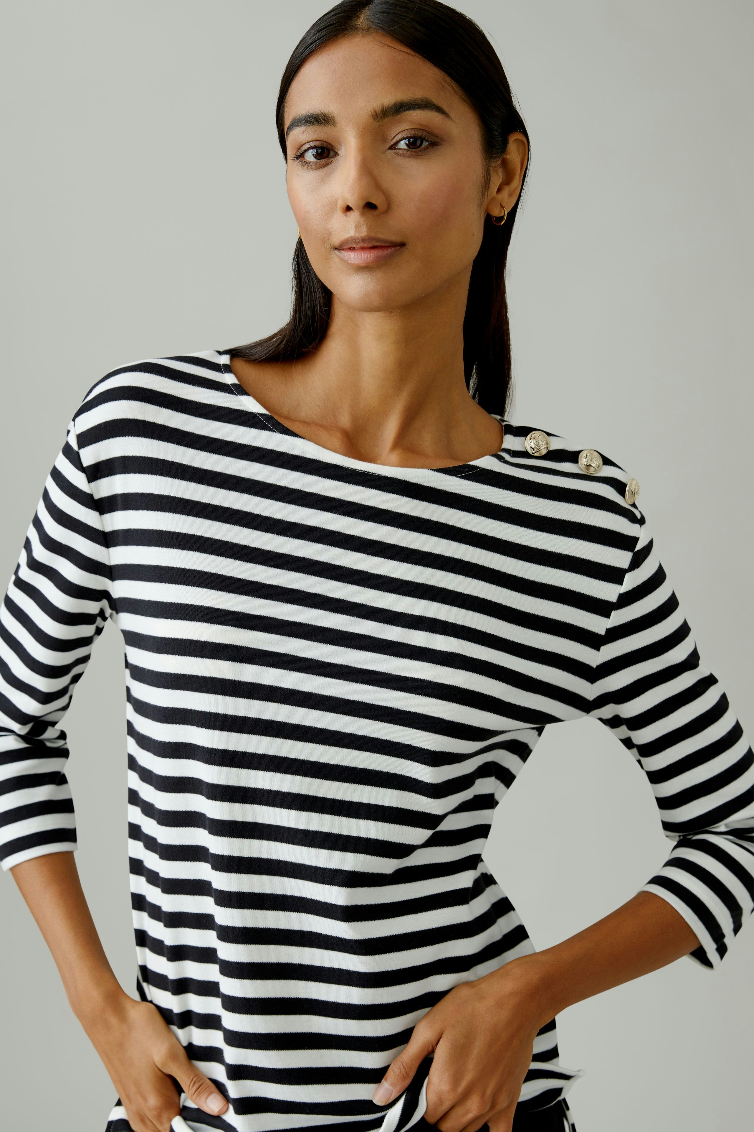 Casual women's long-sleeve shirt: Woman in a black and white striped top with button details.