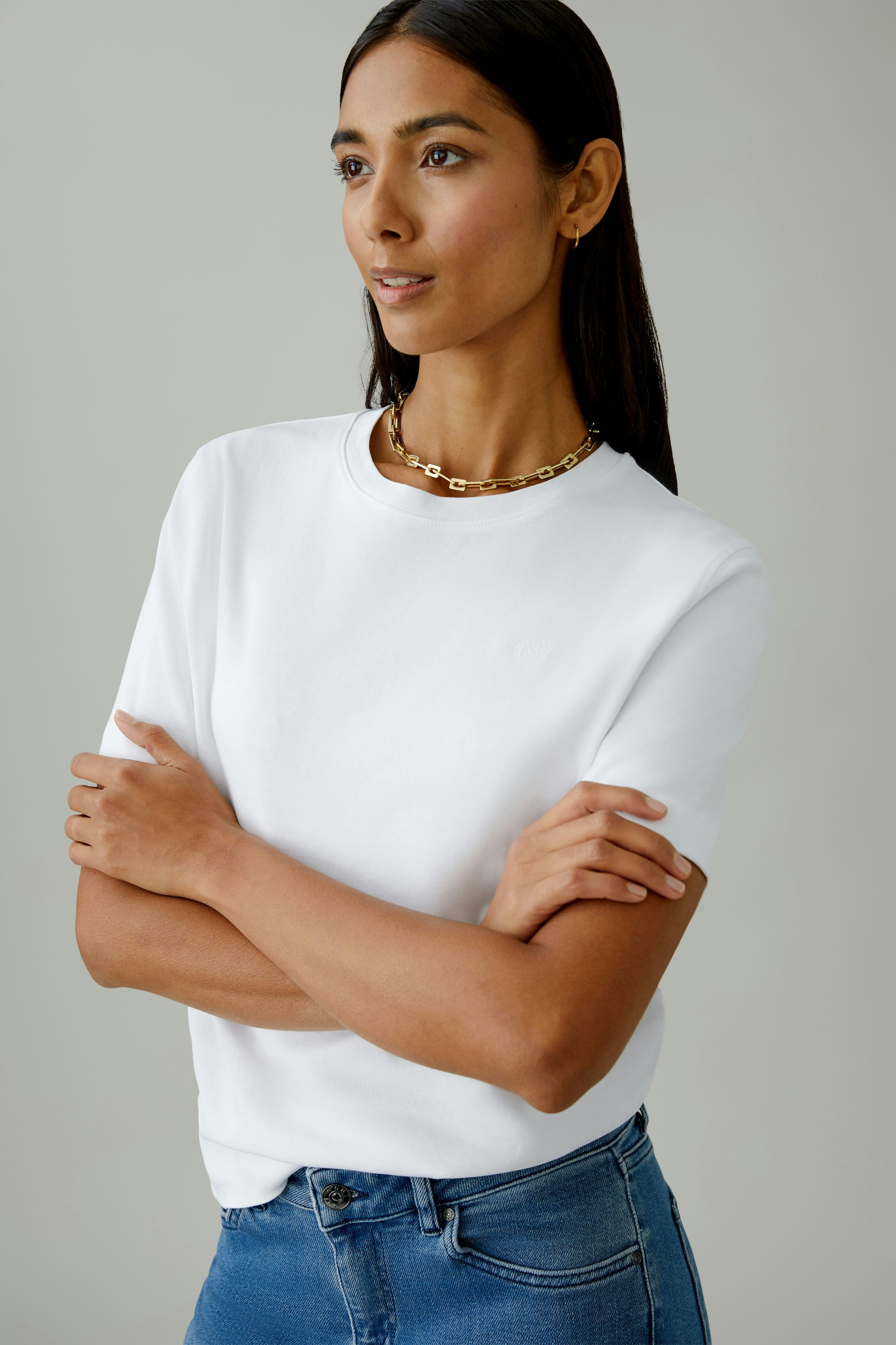 Casual women's T-shirt: Young woman in a white tee, paired with denim, exuding a relaxed vibe.