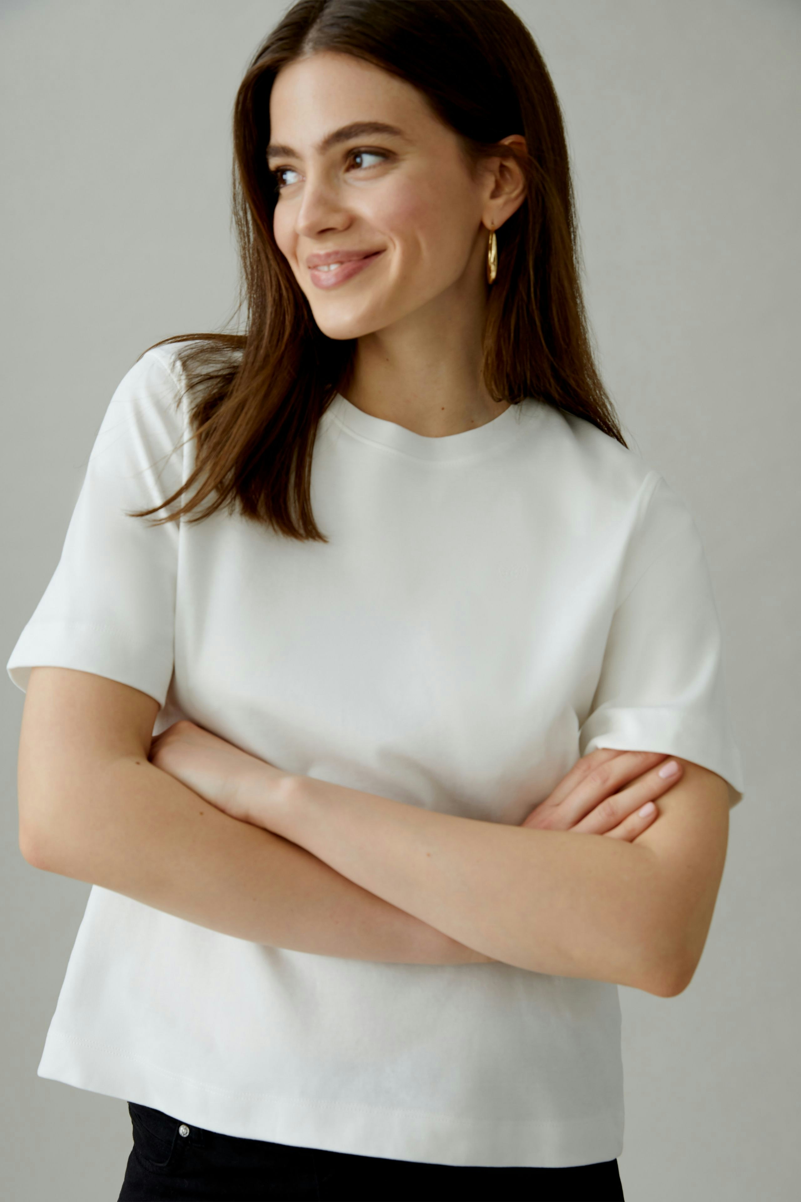 Casual women's T-shirt: Smiling woman in a white short-sleeve top with a relaxed fit.