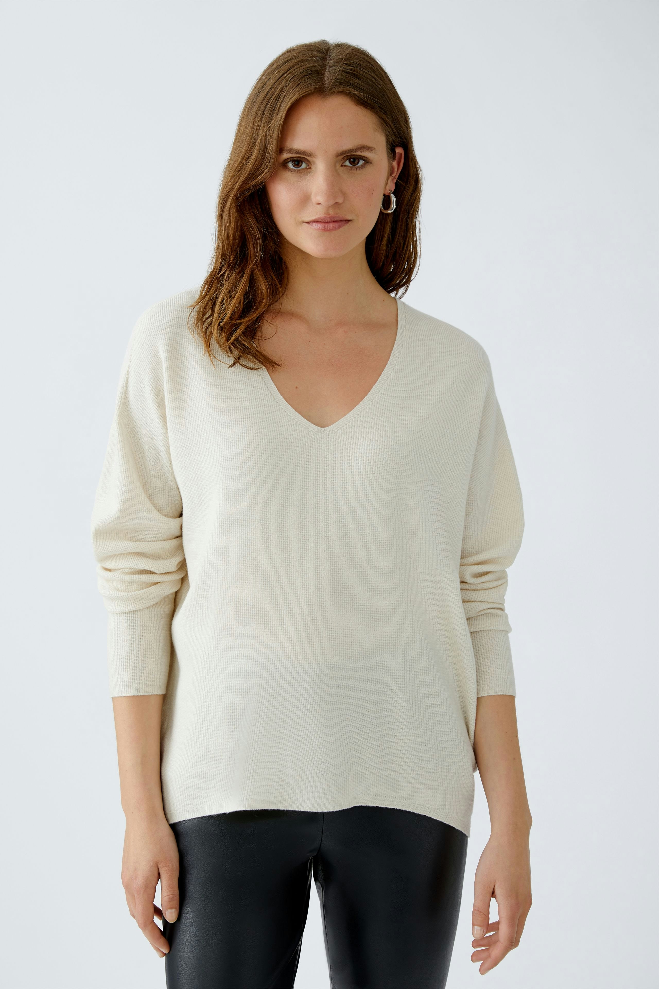 Bequemer Damen-Pullover: Frau in beigem V-Ausschnitt-Pullover mit lässigem Schnitt und langen Ärmeln.