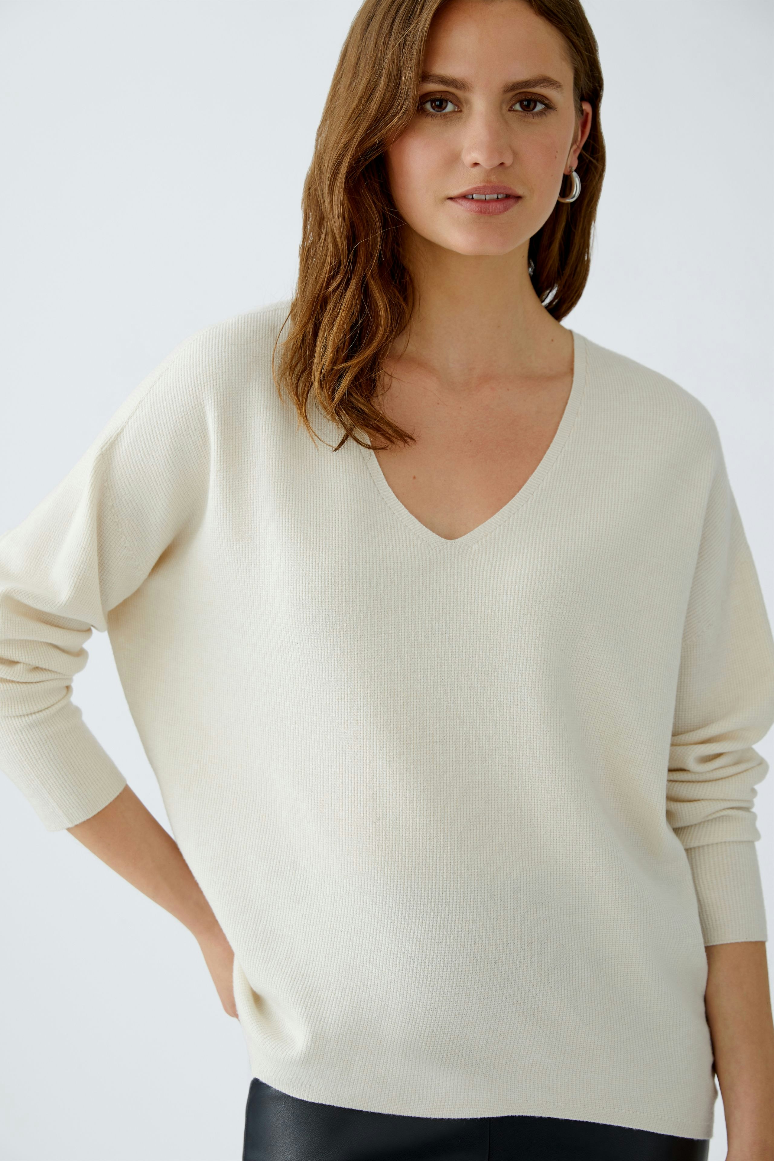 Bequemer Damen-Pullover: Frau in hellem V-Ausschnitt-Pullover mit lässigem Schnitt.