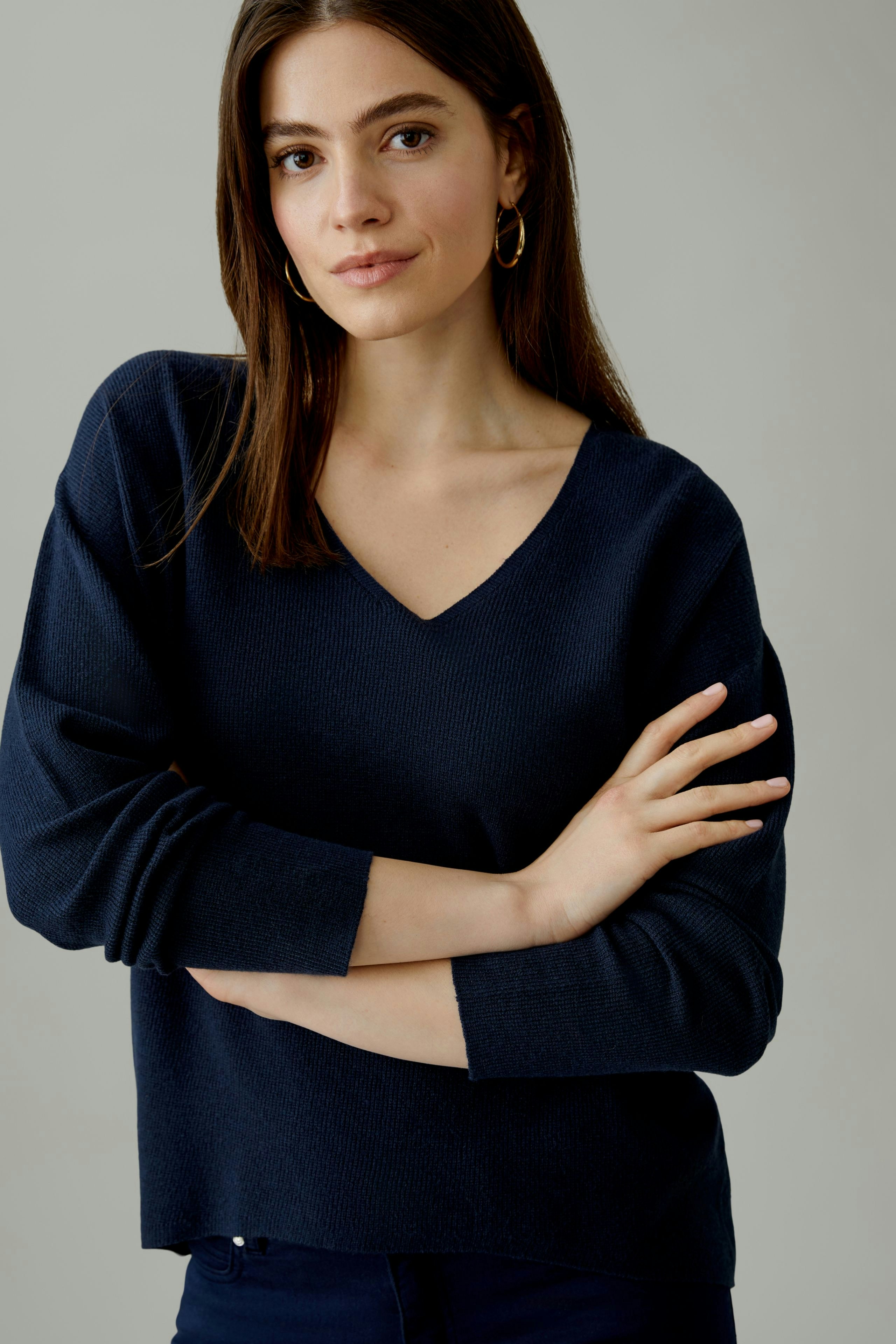 Casual women's pullover: Young woman in a navy V-neck pullover with relaxed fit.