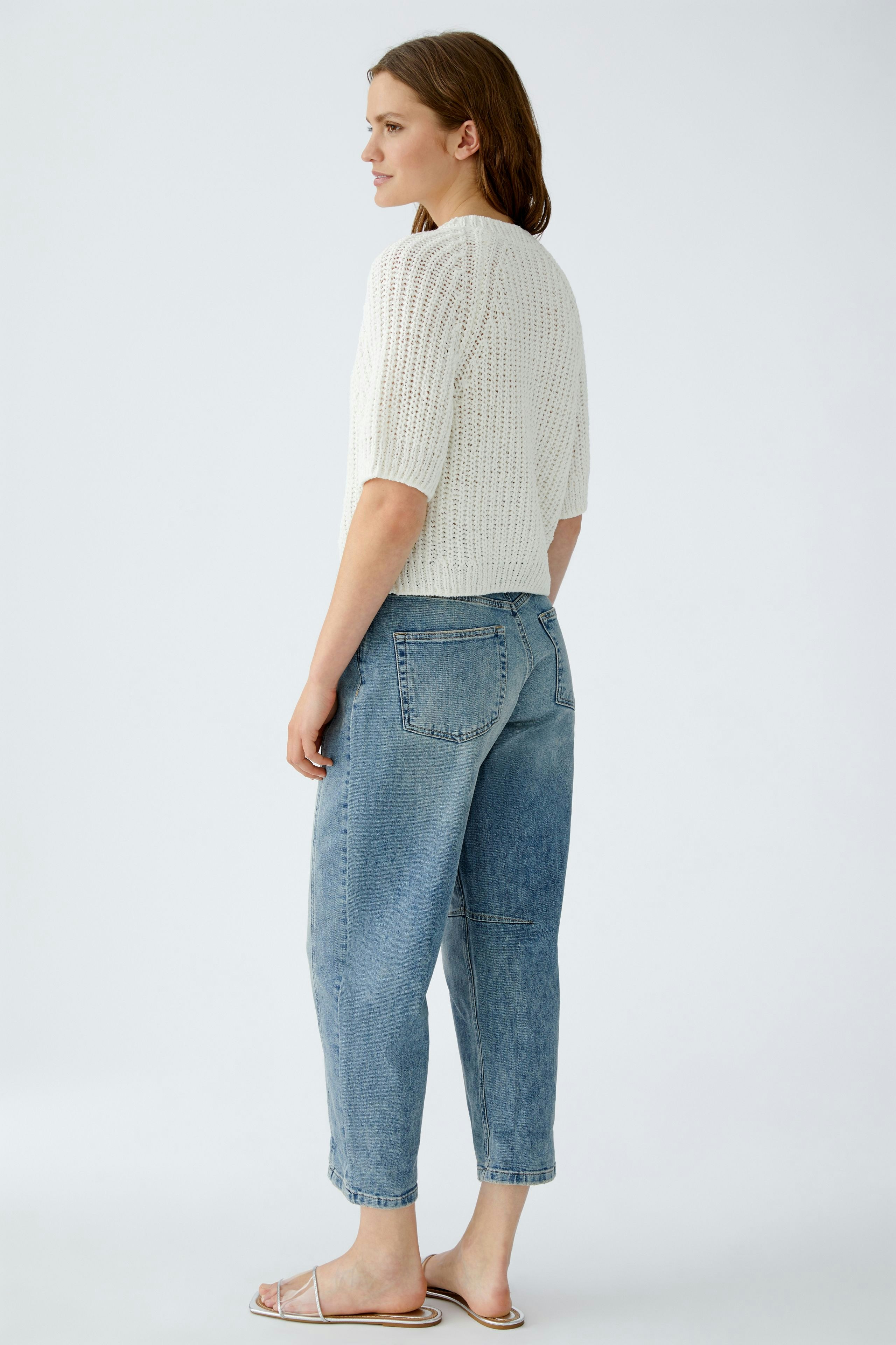 Casual women's cardigan: A woman in a light knitted cardigan paired with relaxed jeans.
