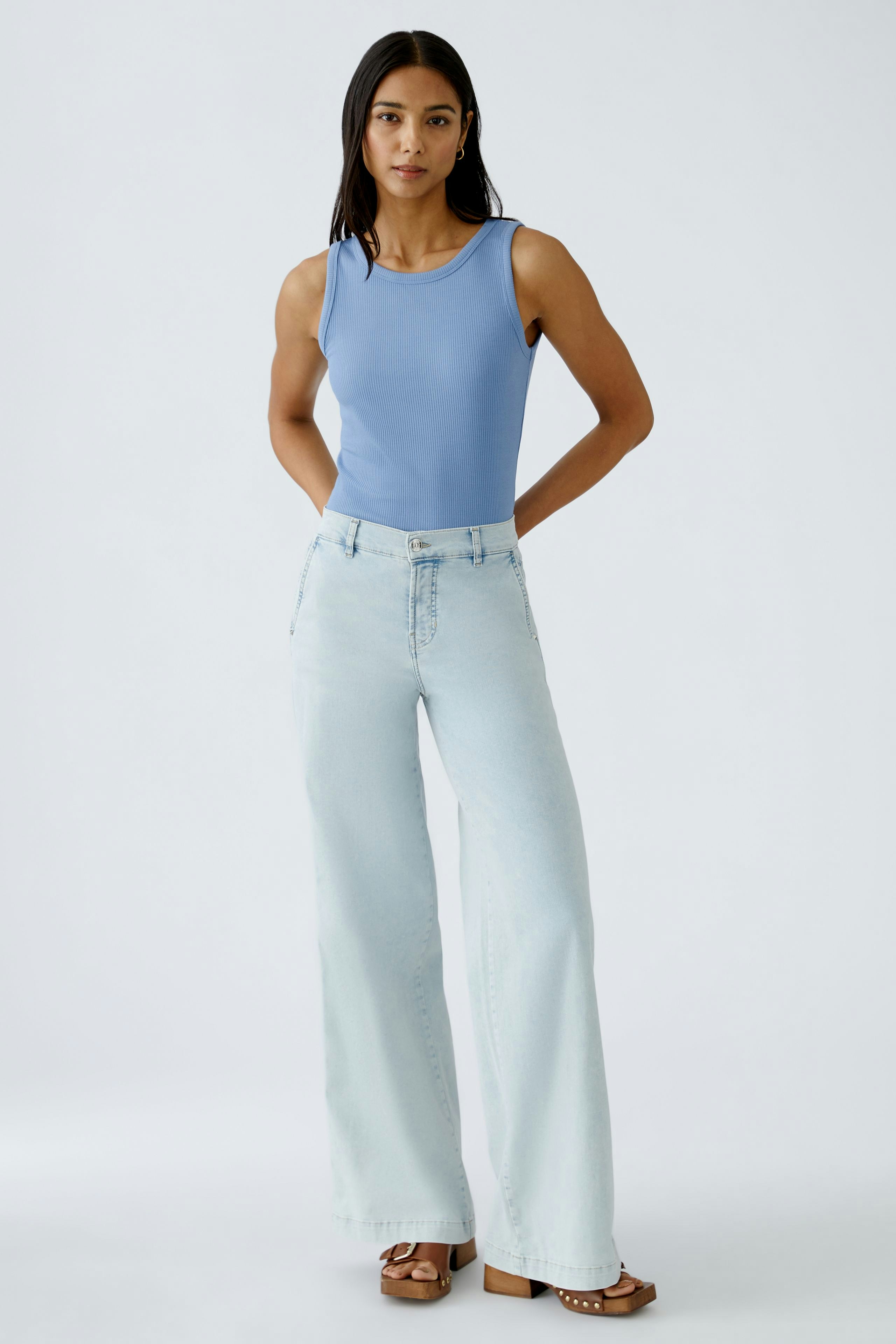 Damen Jeans Flared: Junge Frau in hellblauen, weit geschnittenen Jeans mit lässigem Oberteil.