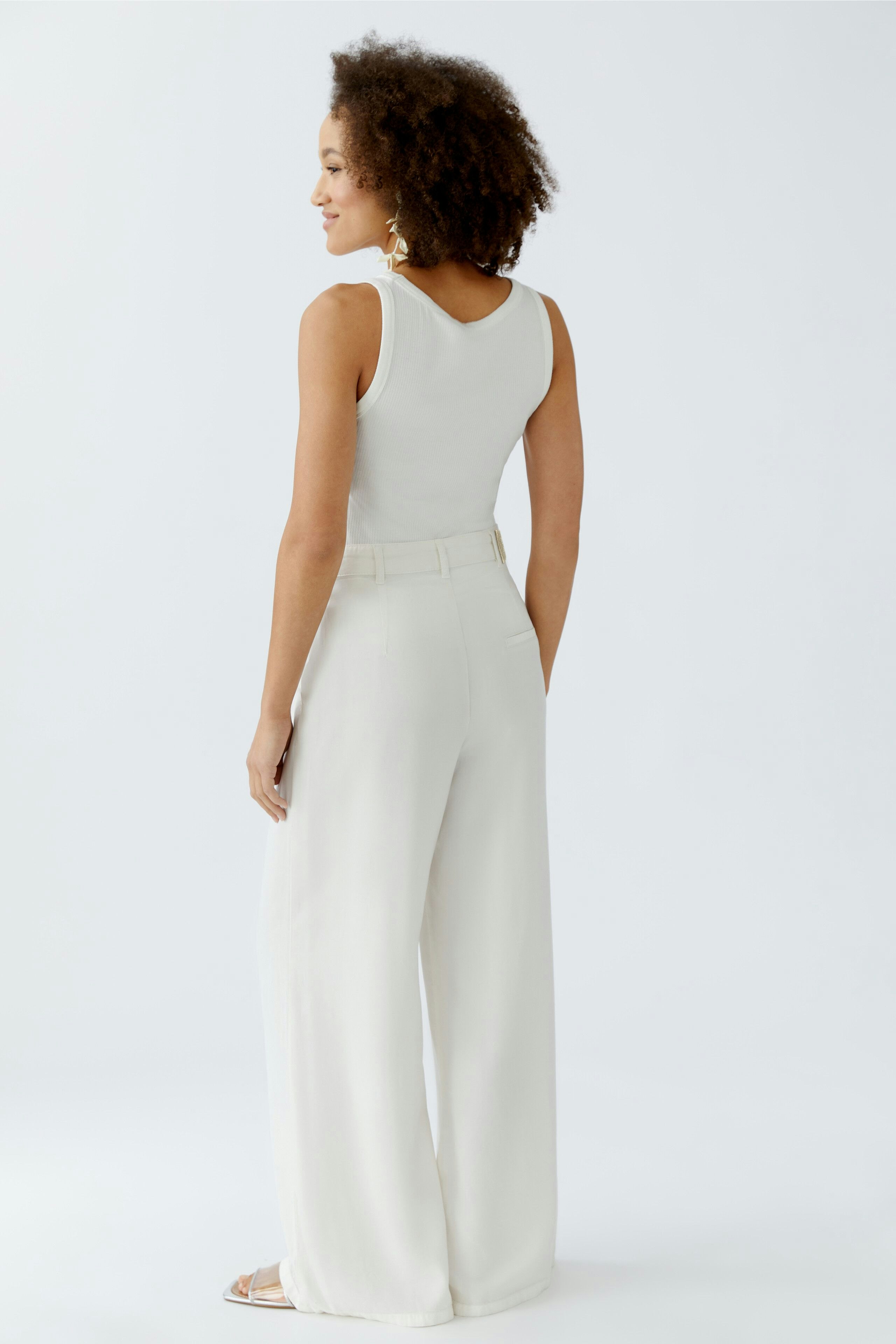 Bequeme Bundfaltenhose: Frau in heller Hose mit weitem Bein und lässigem Schnitt, ideal für den Alltag.