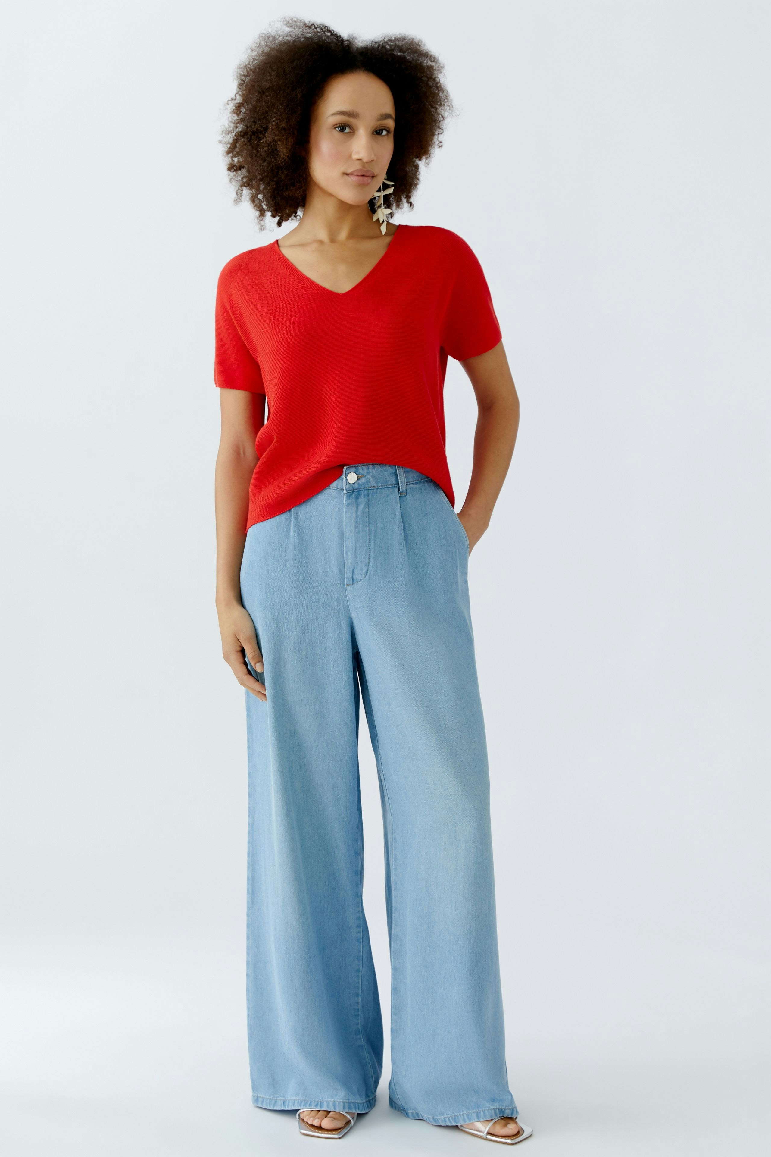 Roter Damen-Pullover mit V-Ausschnitt, kombiniert mit lässigen, weiten Jeans.