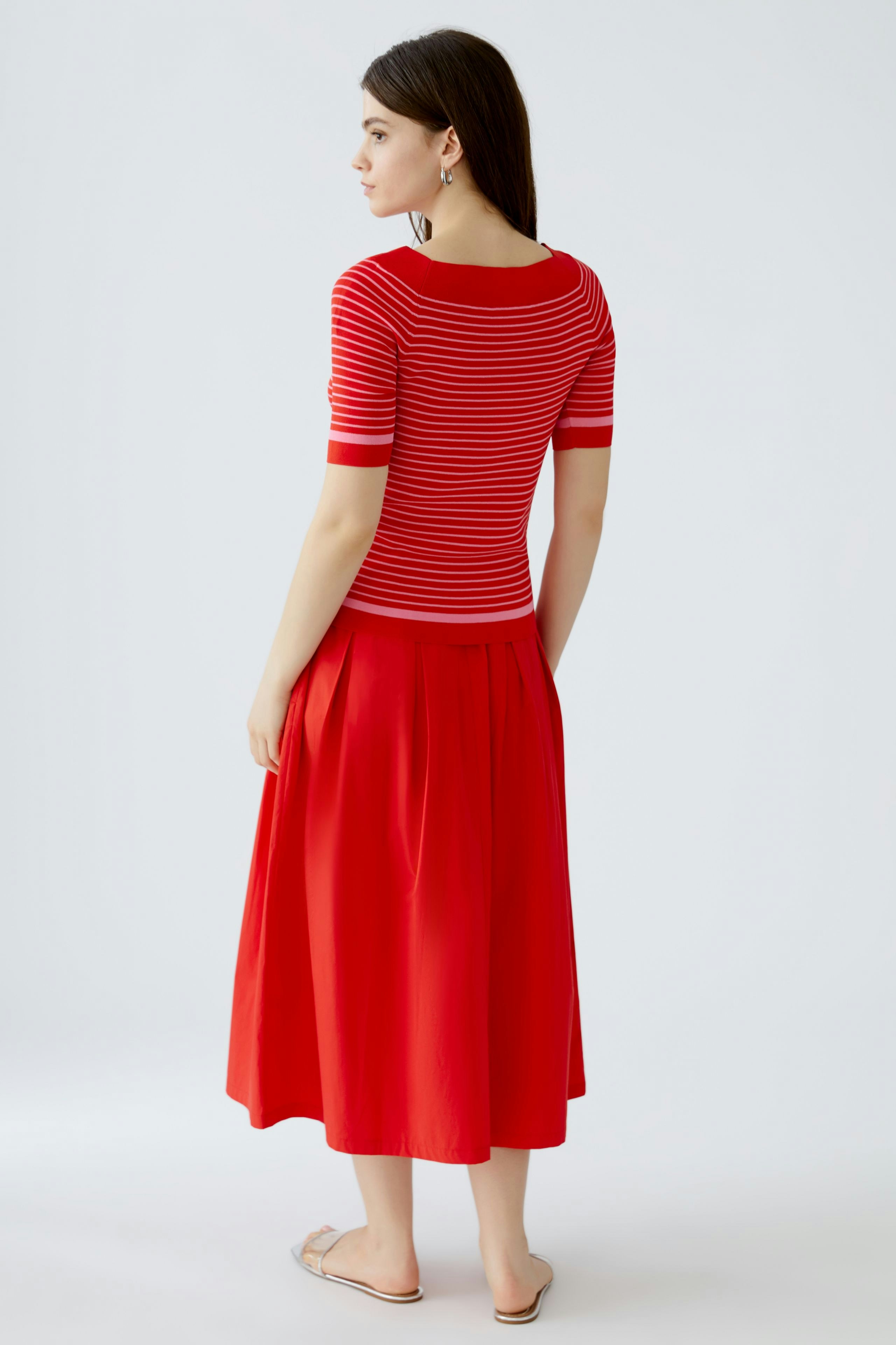 Damen-Pullover: Frau trägt einen rot-gestreiften Pullover mit kurzen Ärmeln und kombiniert ihn mit einem roten Rock.