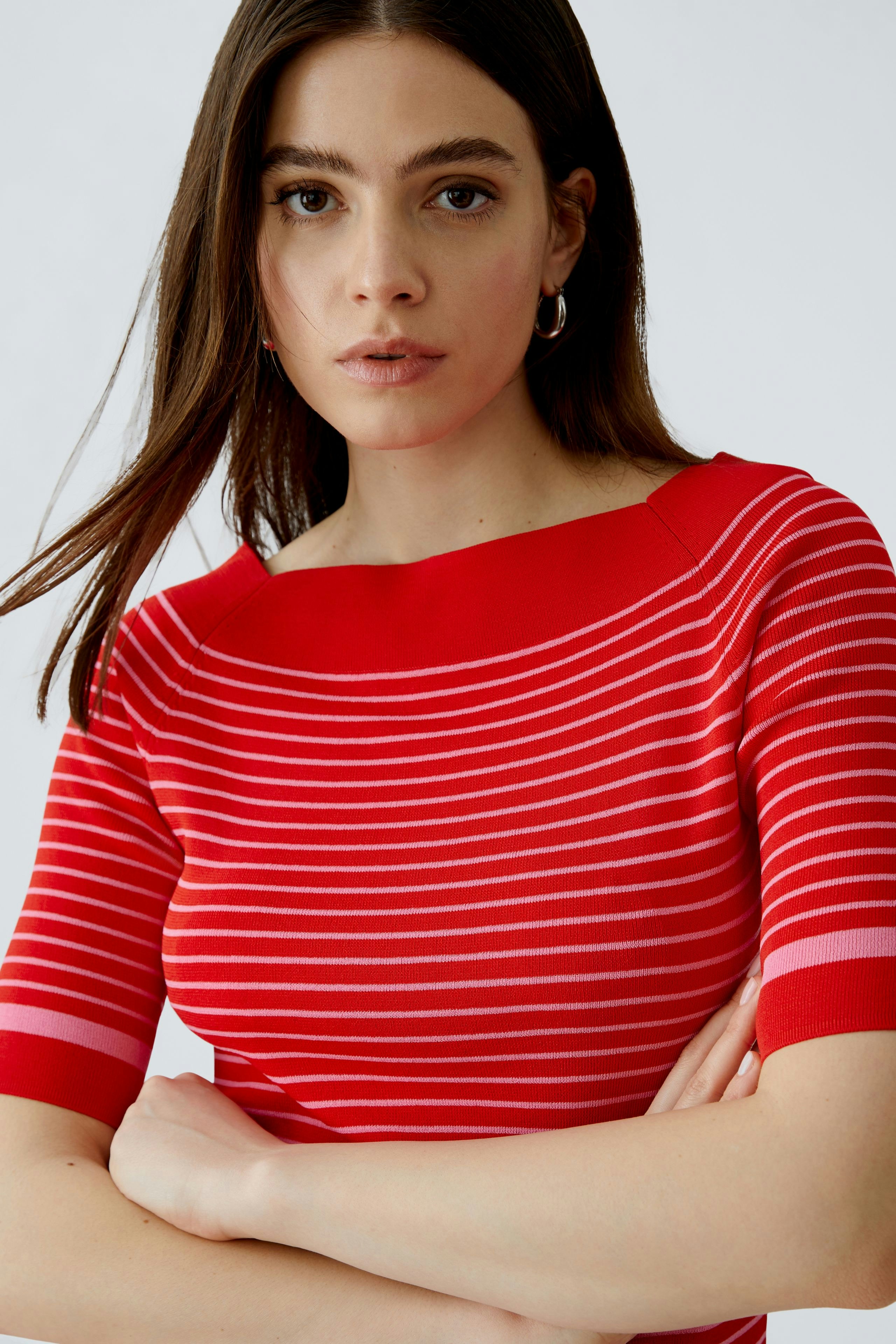 Damen-Pullover: Frau in rot-gestreiftem Pullover mit weitem Ausschnitt und kurzen Ärmeln blickt direkt in die Kamera.