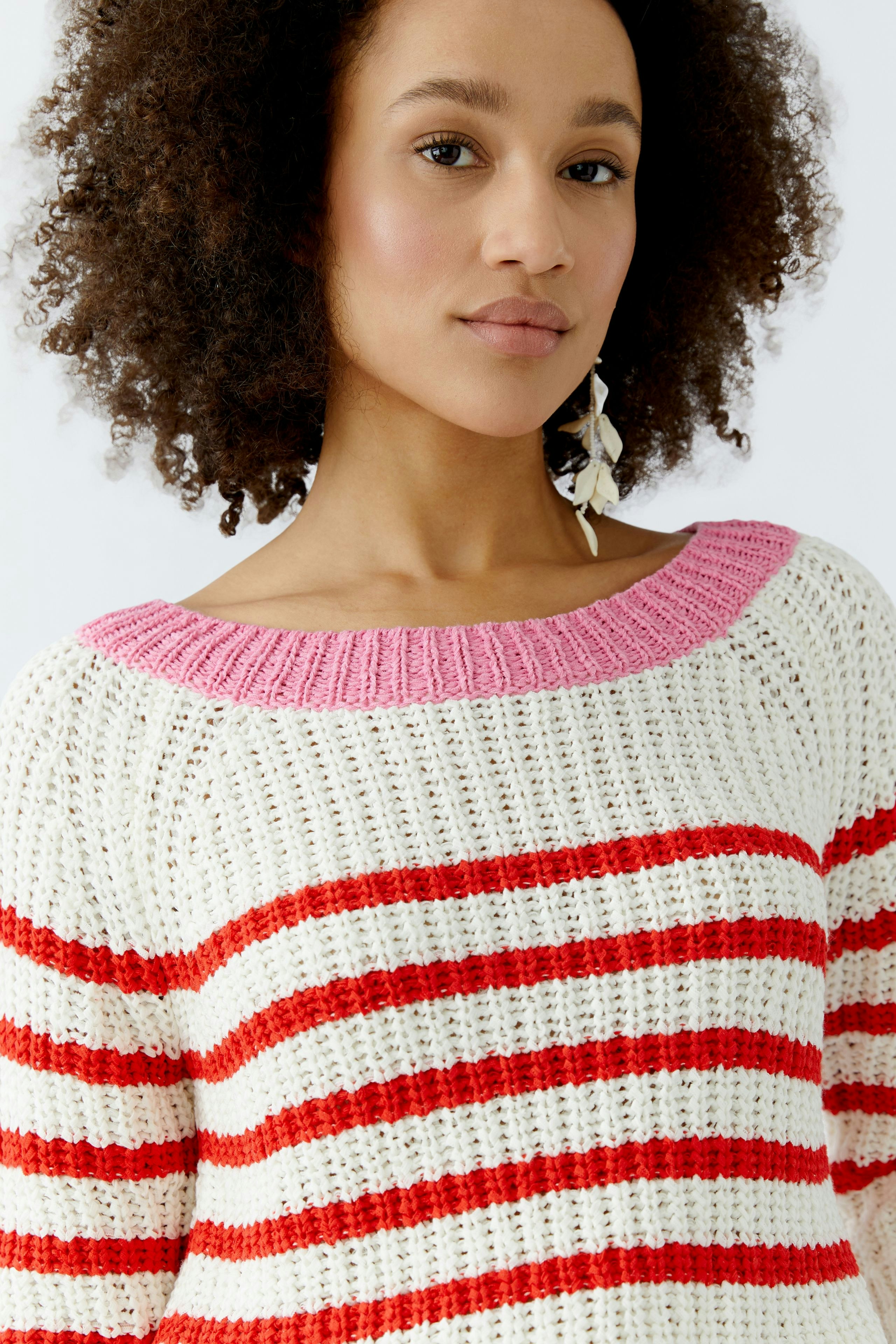 Casual women's pullover: Young woman in a striped knit pullover with pink neckline, smiling confidently.